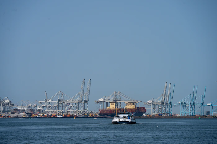 A boat passing a commercial port with cranes in Rotterdam
