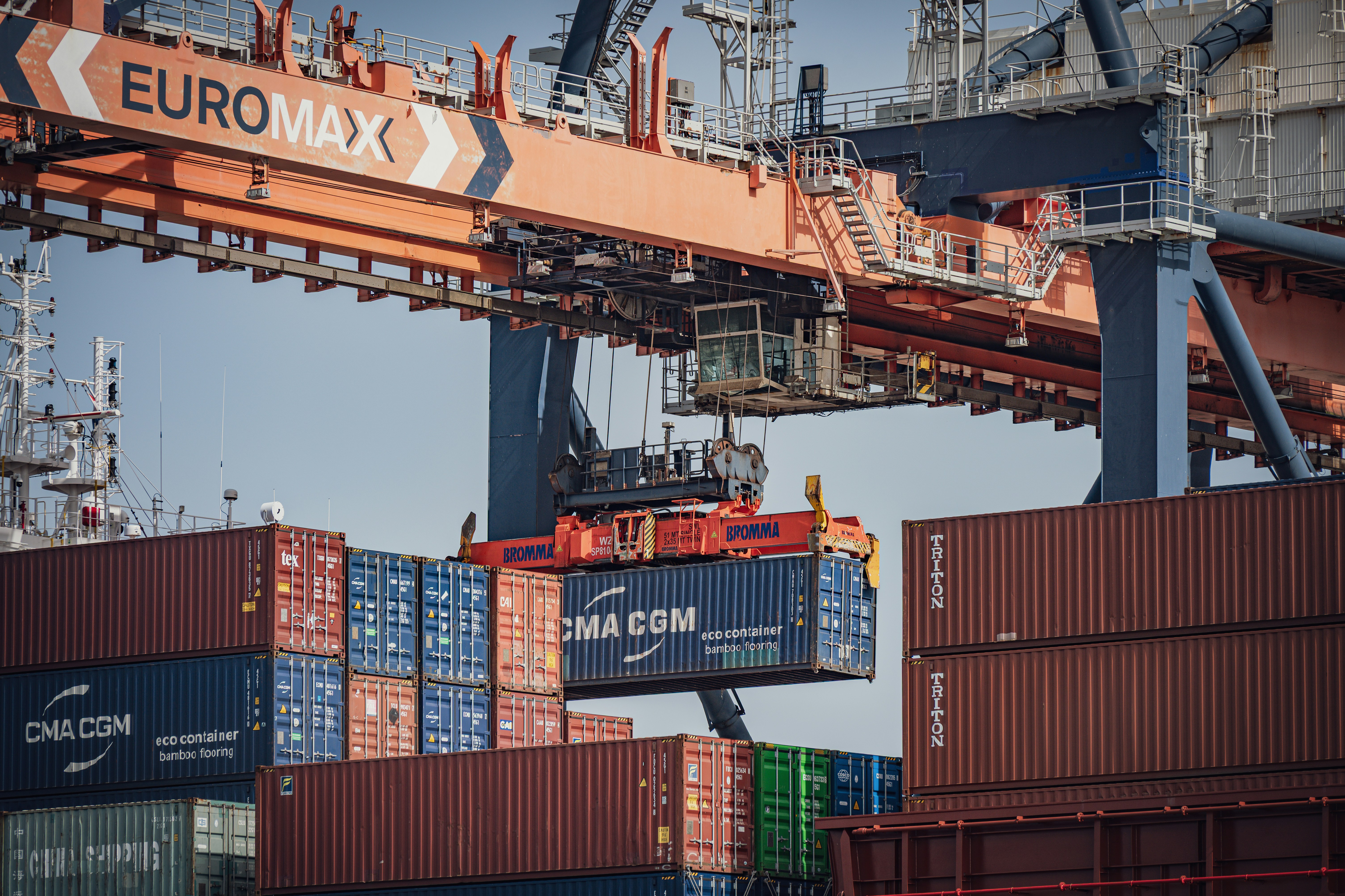 Euromax crane moves a blue shipping container at a port.