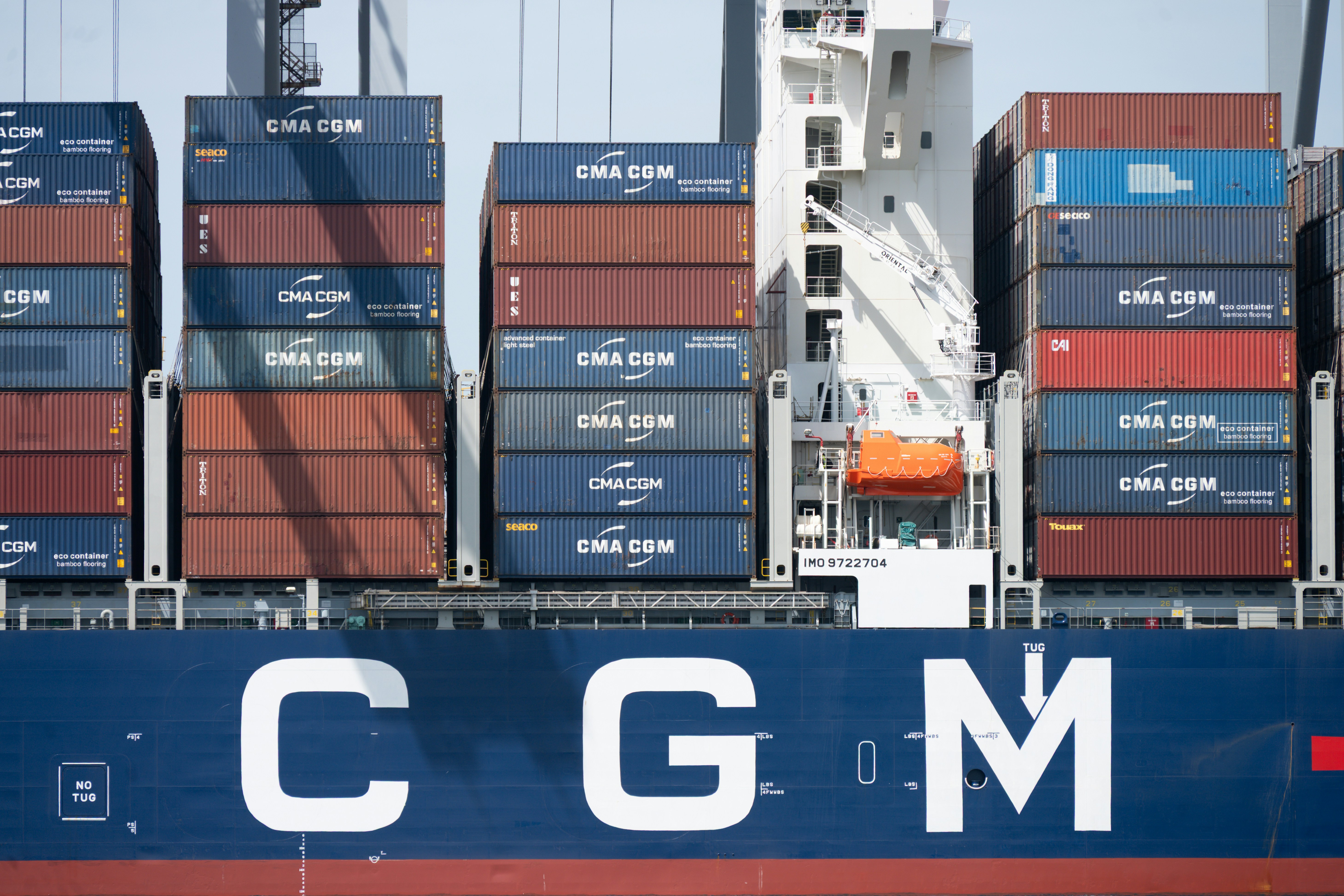 Cargo ship with stacked containers and "c g m" branding