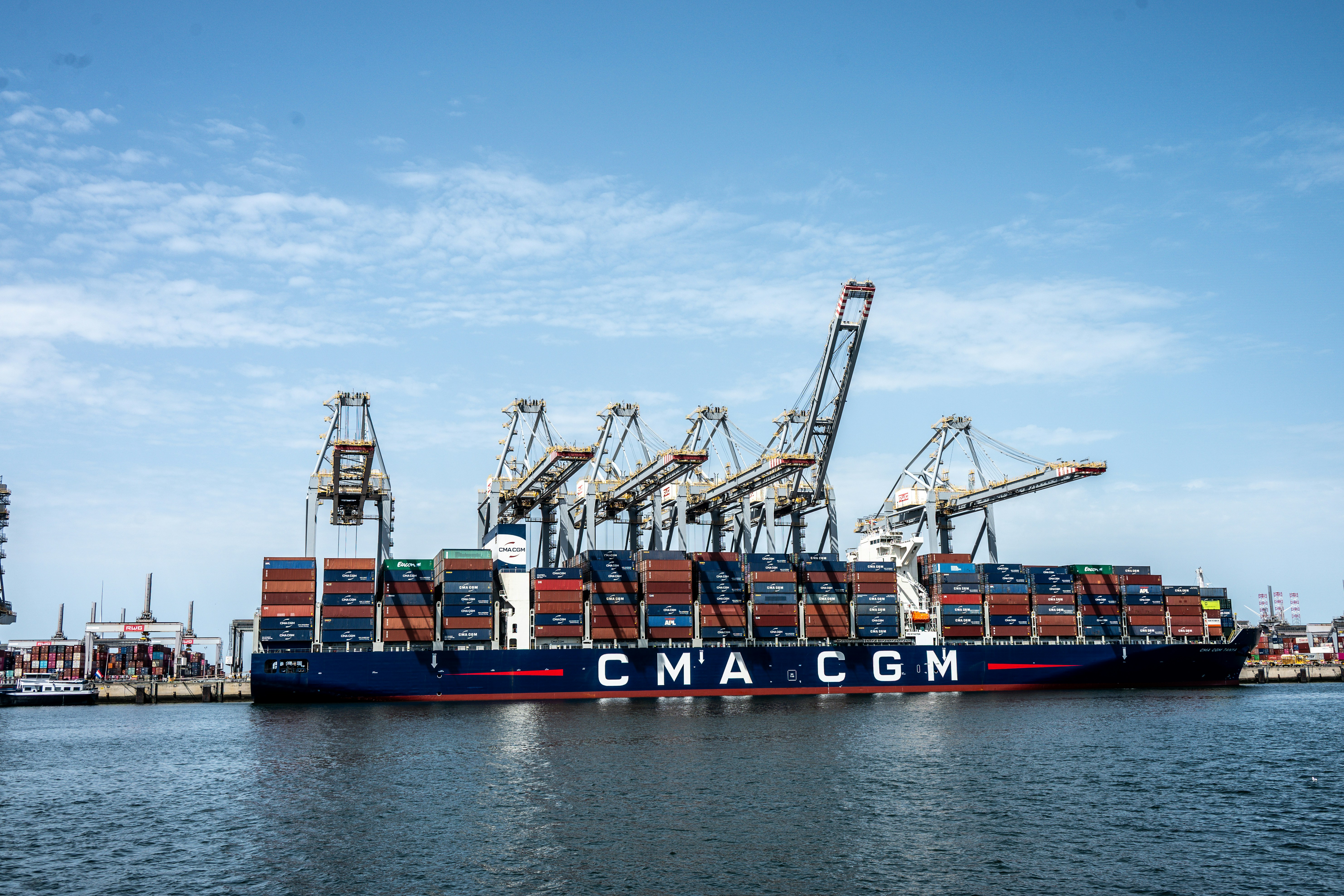 Container ship cma cgm docked with cranes under blue sky