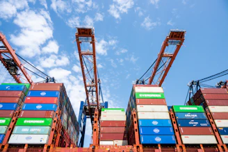Cranes loading colorful shipping containers under a blue sky.