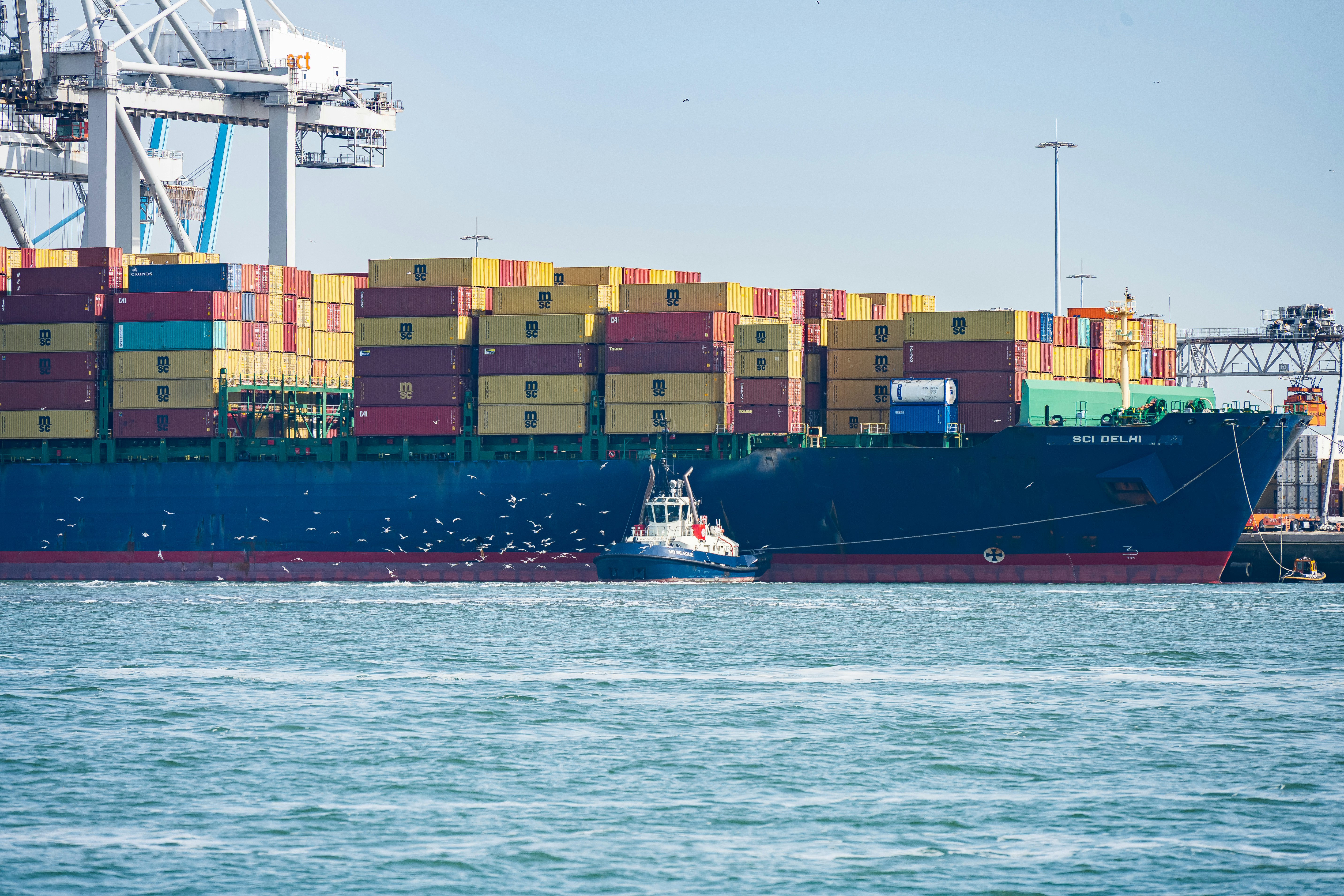Large container ship with tugboat representing marine financing companies