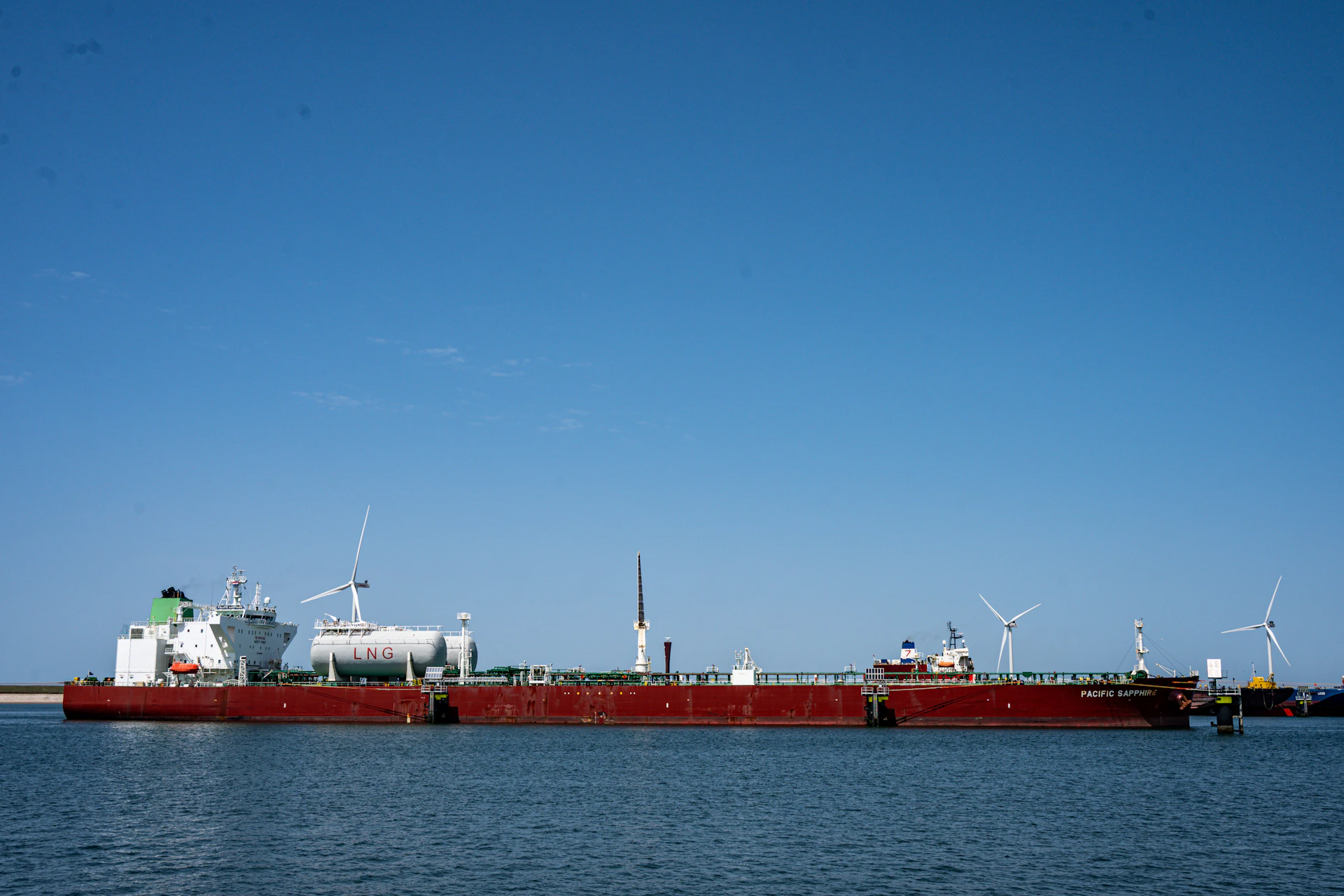 Large barge transporting multiple wind turbines on calm water
