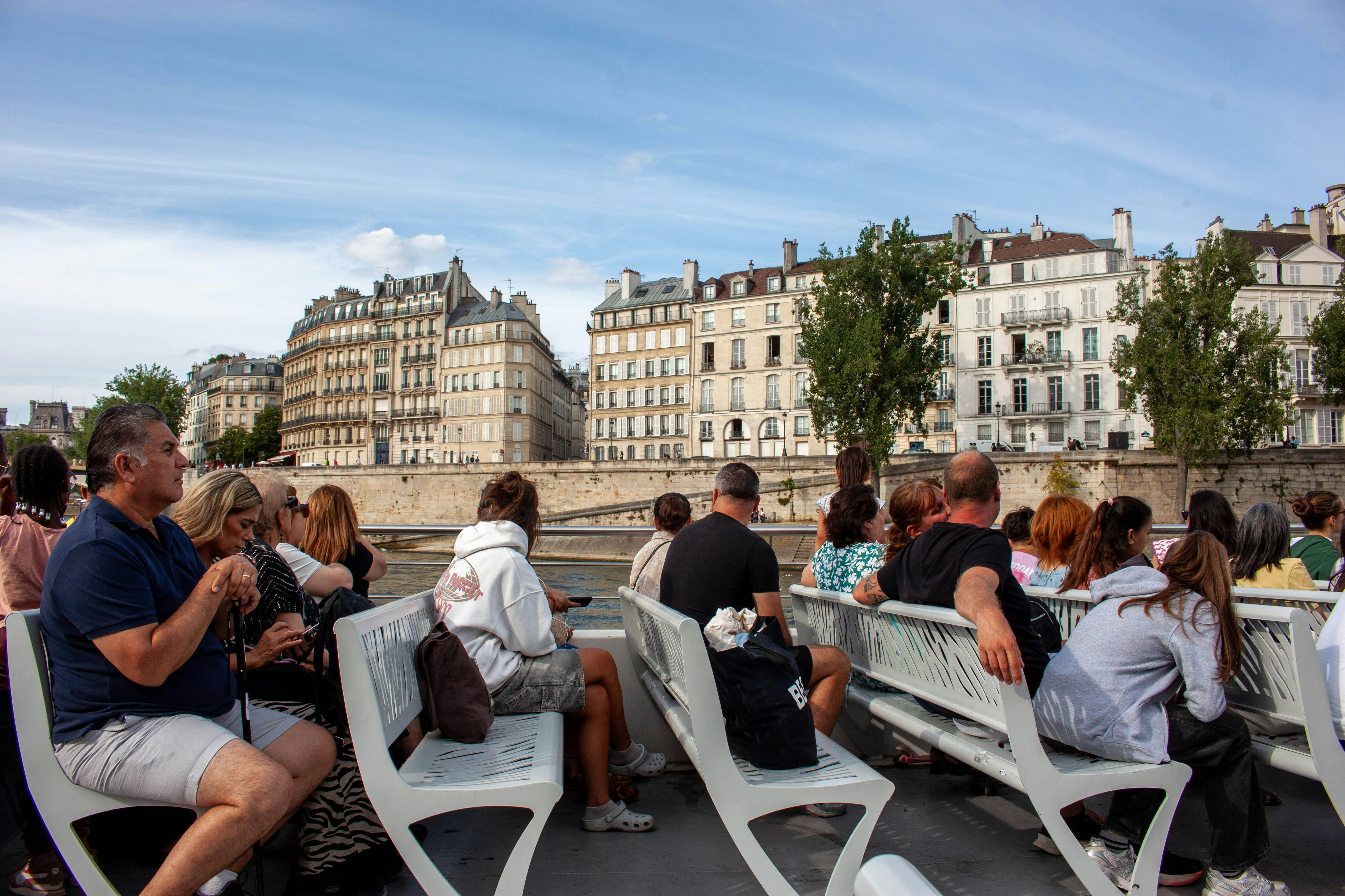 Boat passengers enjoying a scenic view of riverside architecture - private wine tour paris