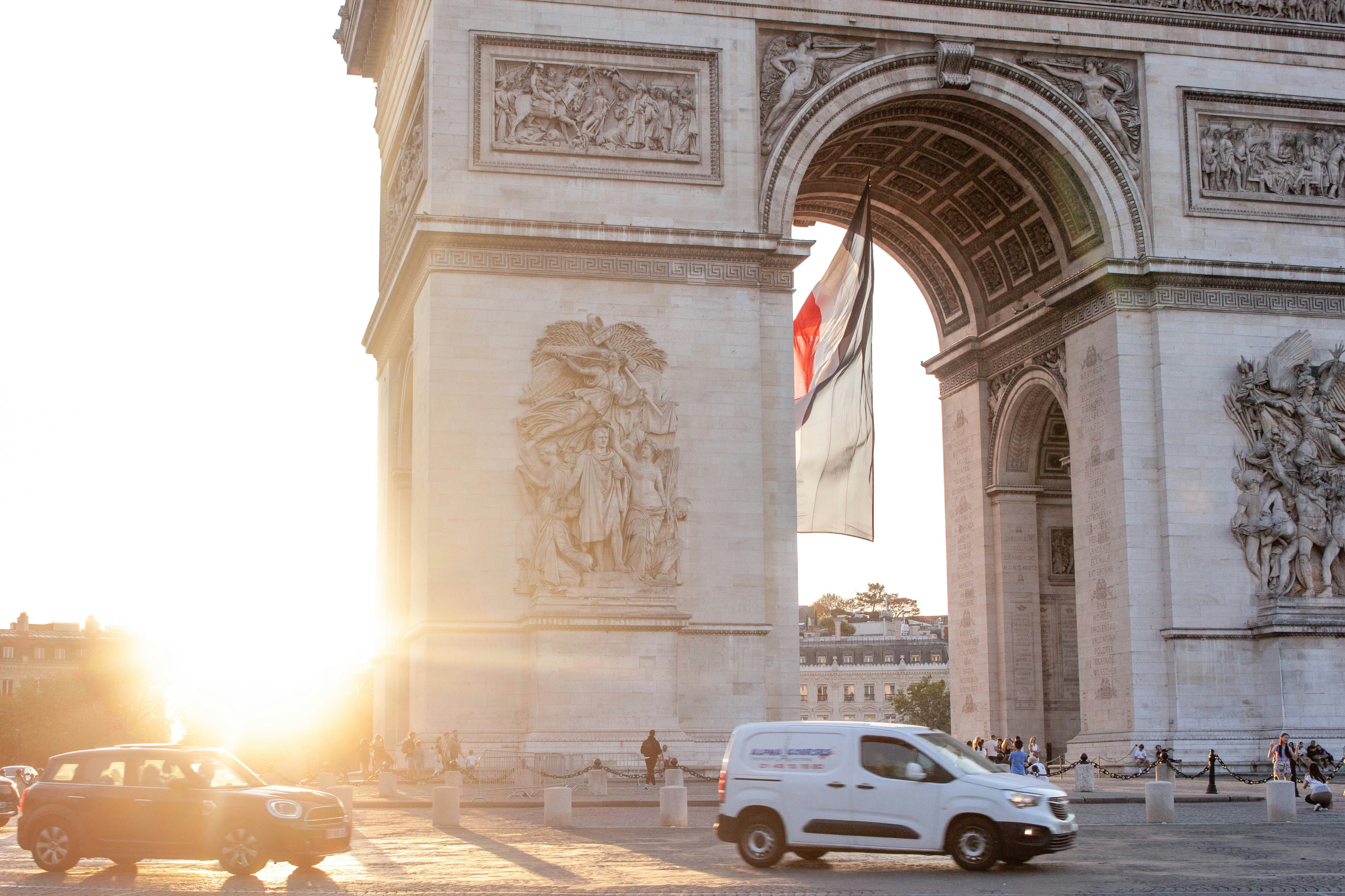Arco di triunfo immerso nella calda luce del tramonto con i veicoli