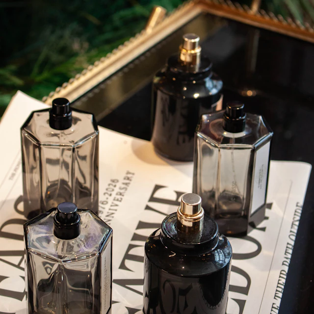 Five perfume bottles standing on a newspaper in a decorative tray