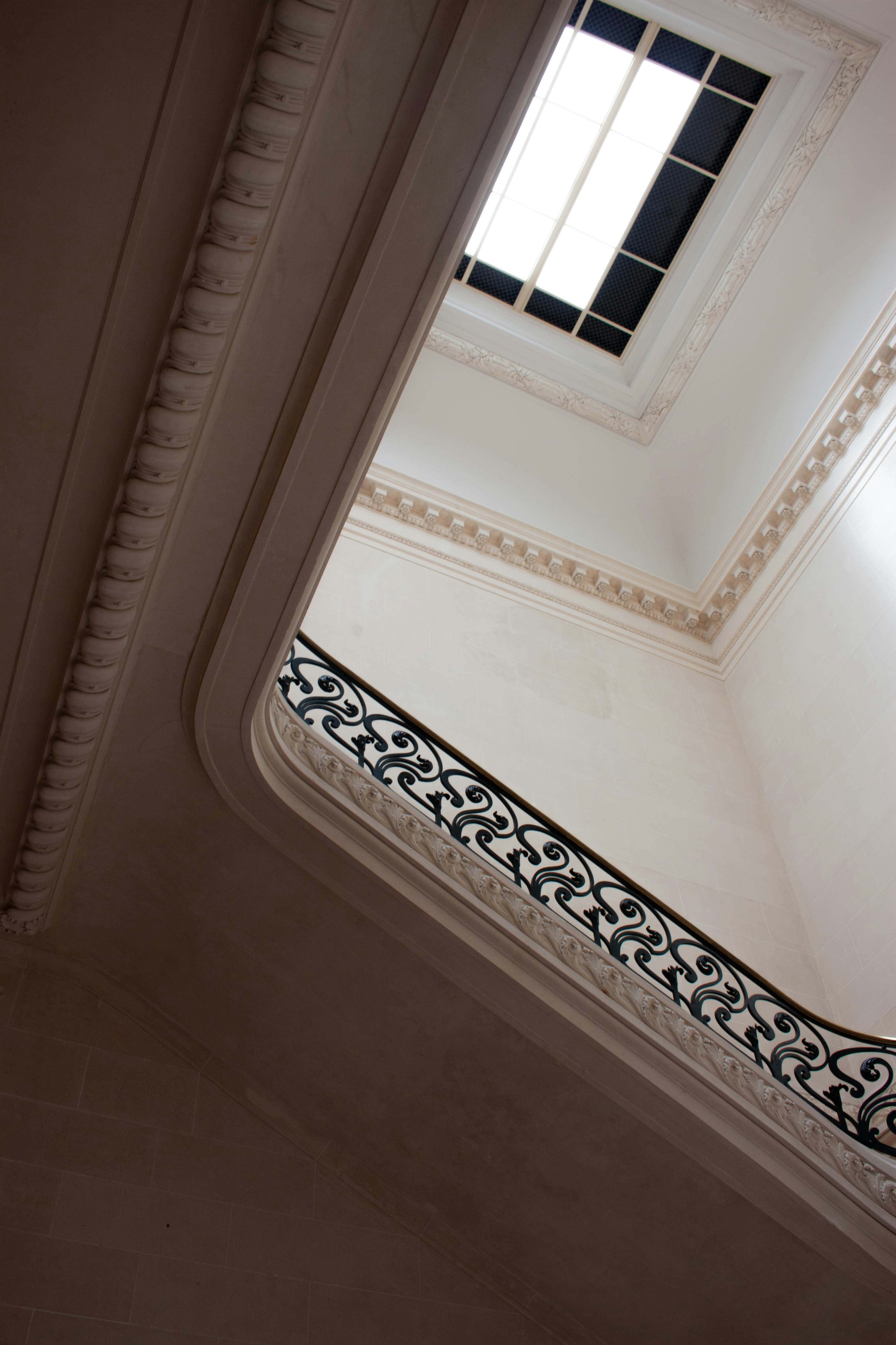 Elegante scala bianca con ringhiera ornata che conduce a un lucernario