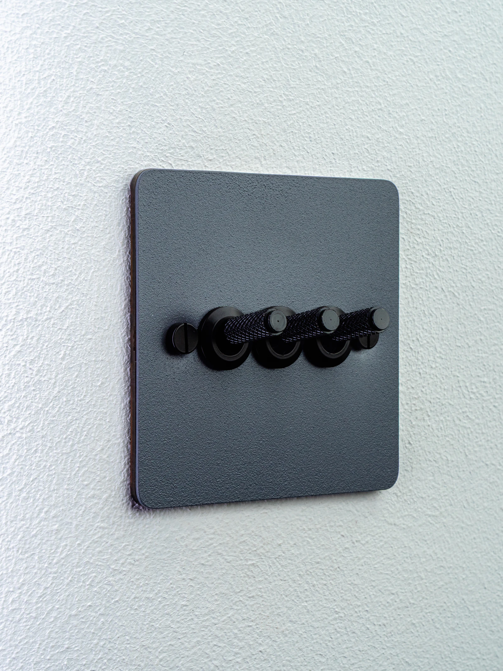 Matte black three-gang toggle light switch on a white wall