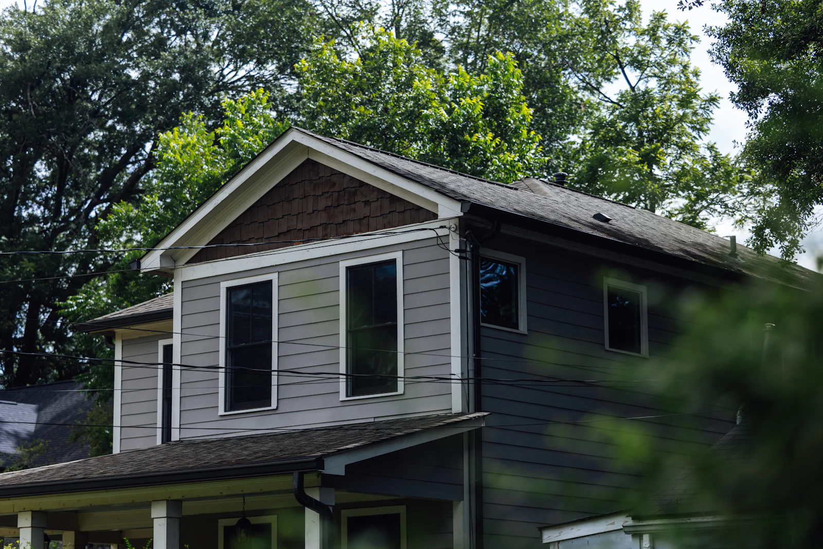 Gray home surrounded by tall green trees