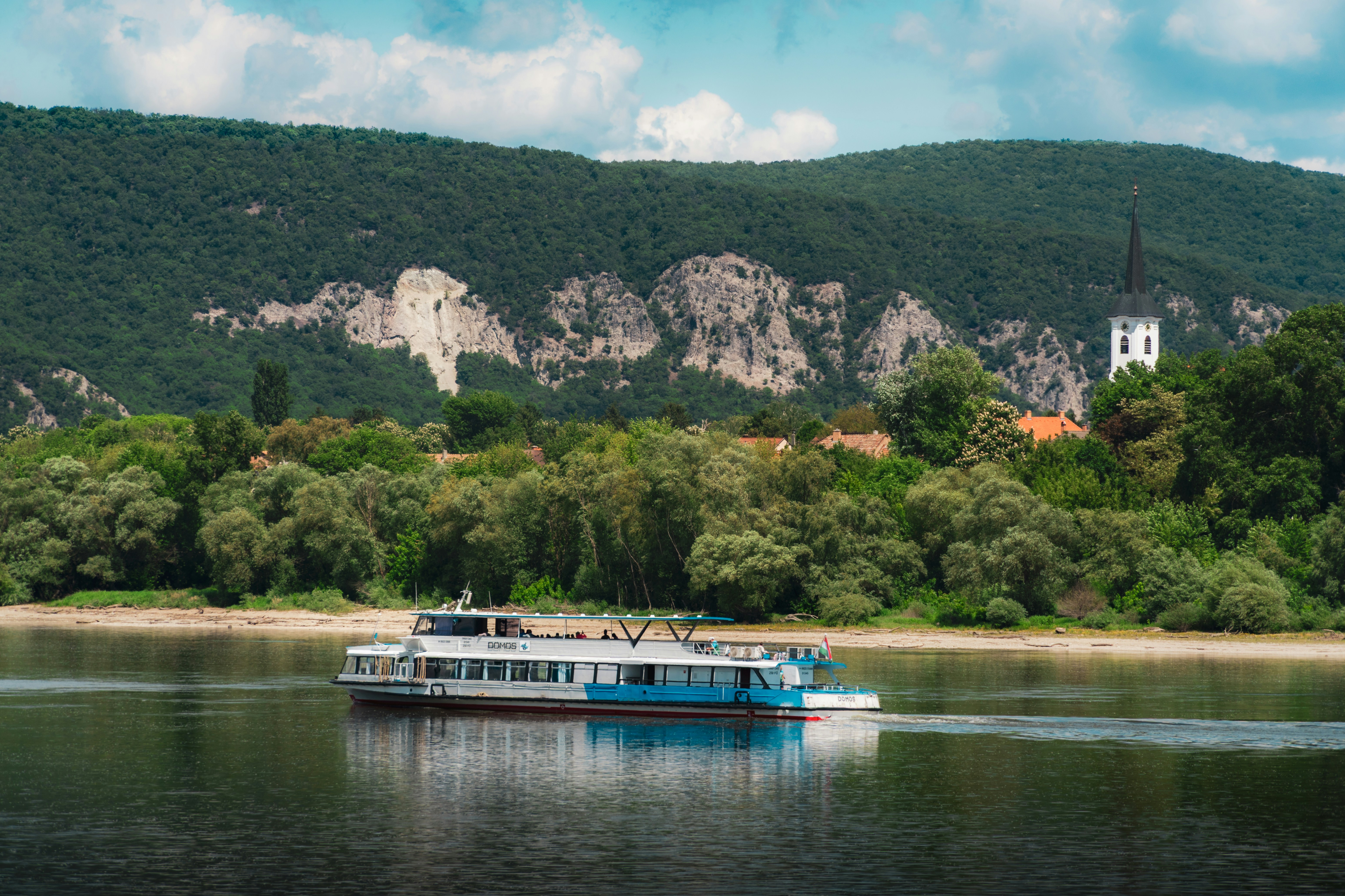 Ferry on a river with a village and forested mountains
