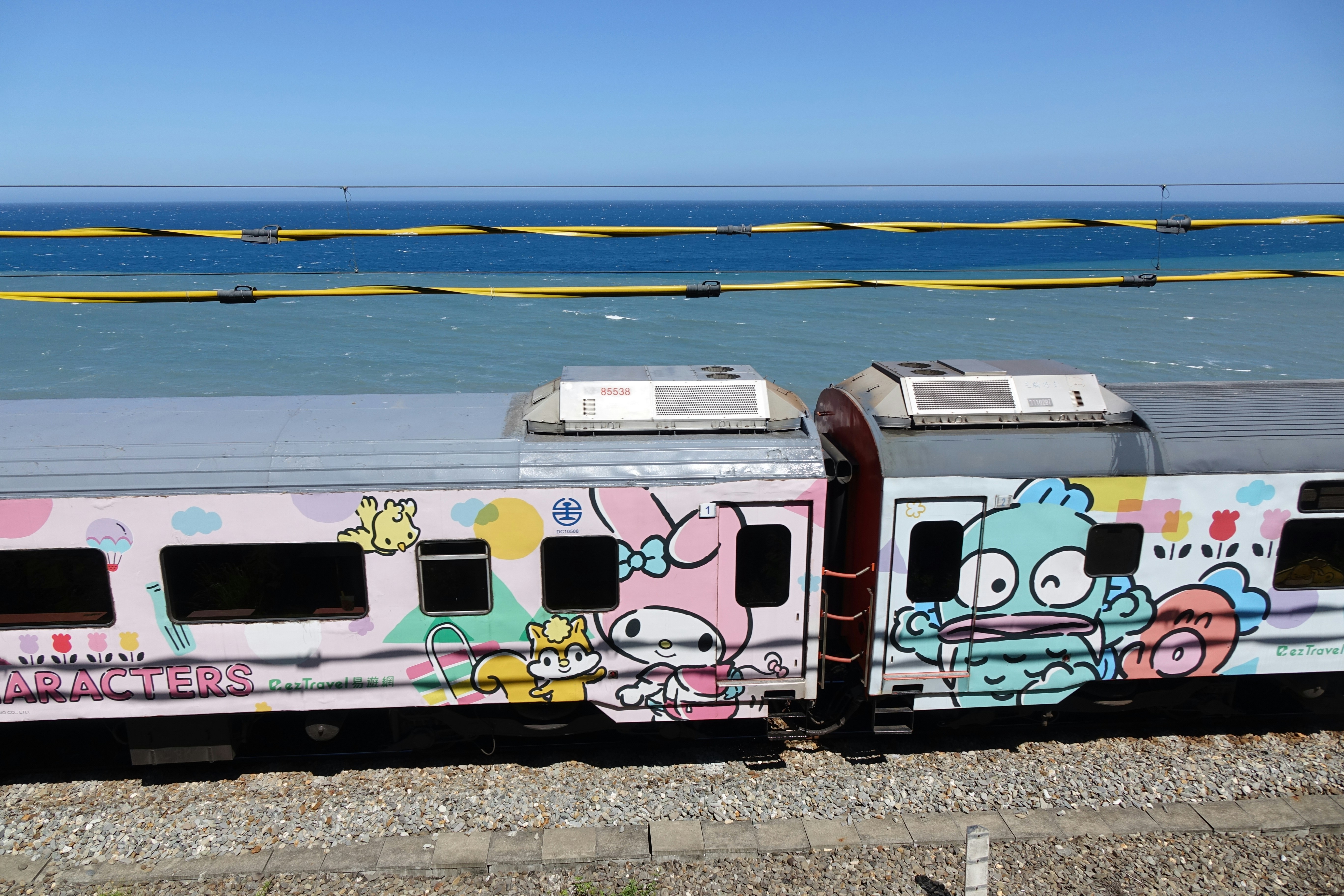 Dois trens coloridos de desenho animado estacionados perto do oceano