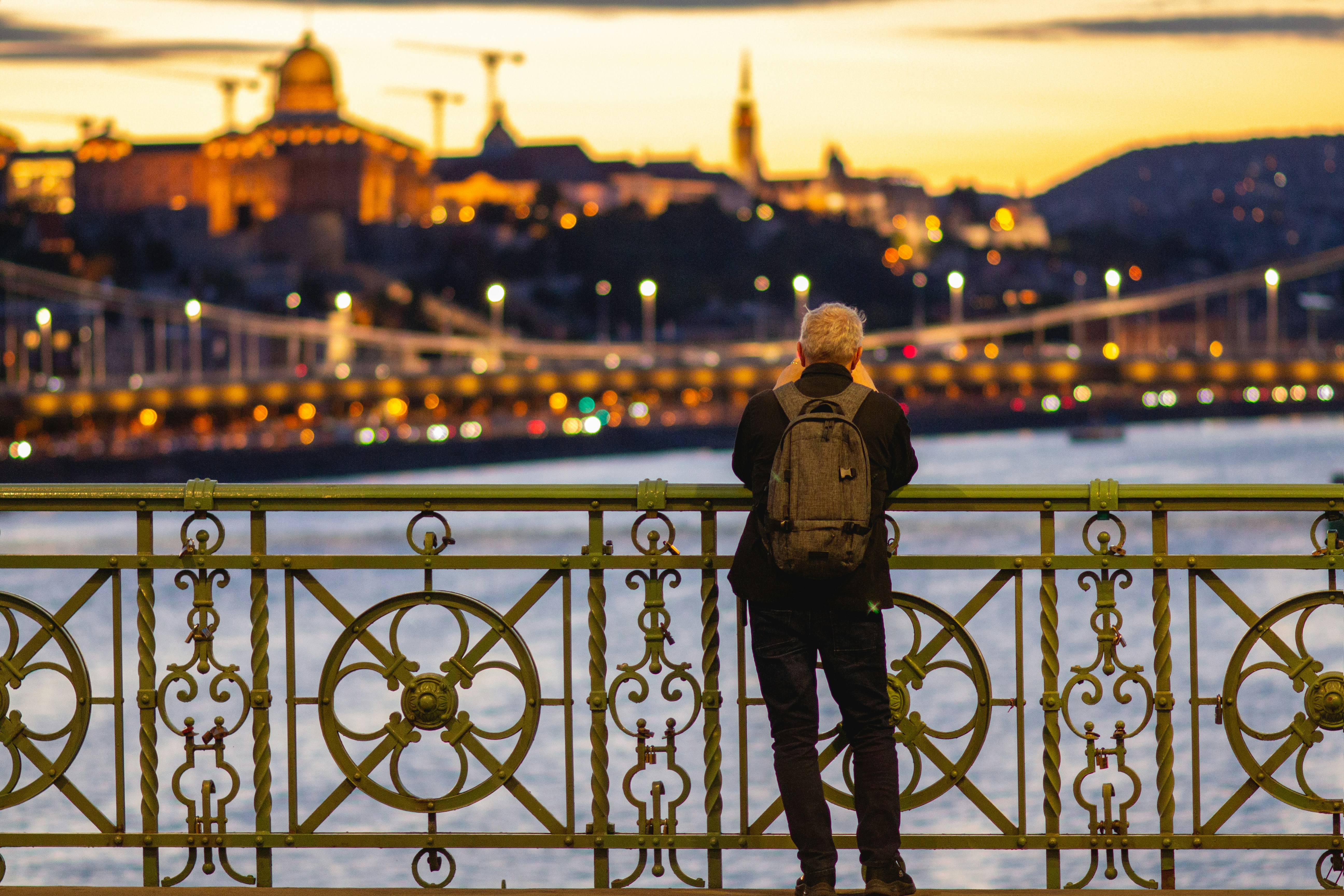 Reisender auf der Brücke bewundert die erleuchtete Skyline der Stadt bei Sonnenuntergang.