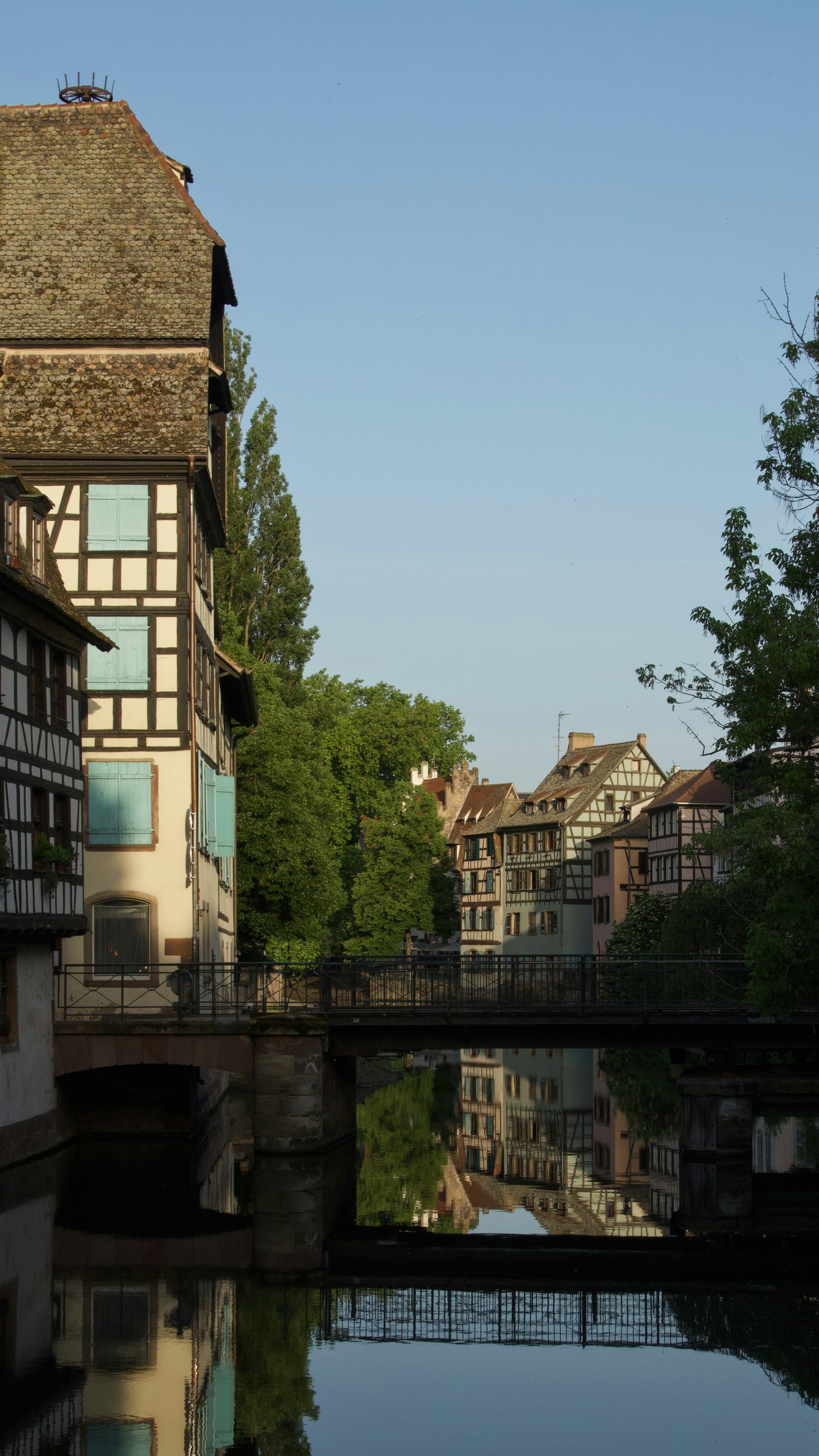 Historic buildings and bridge reflected in a calm canal