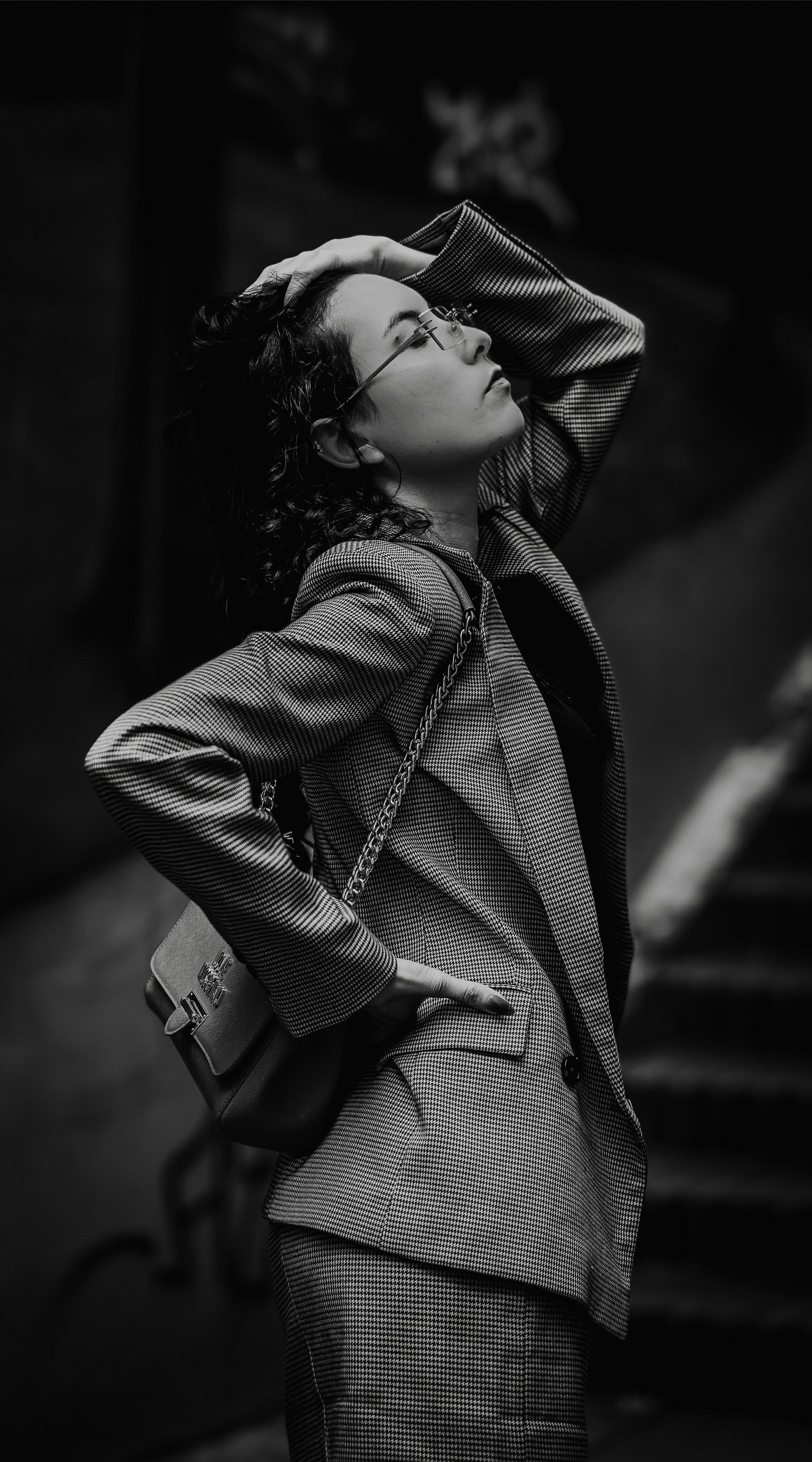 Stylische Frau im Blazer und Brille blickt auf.