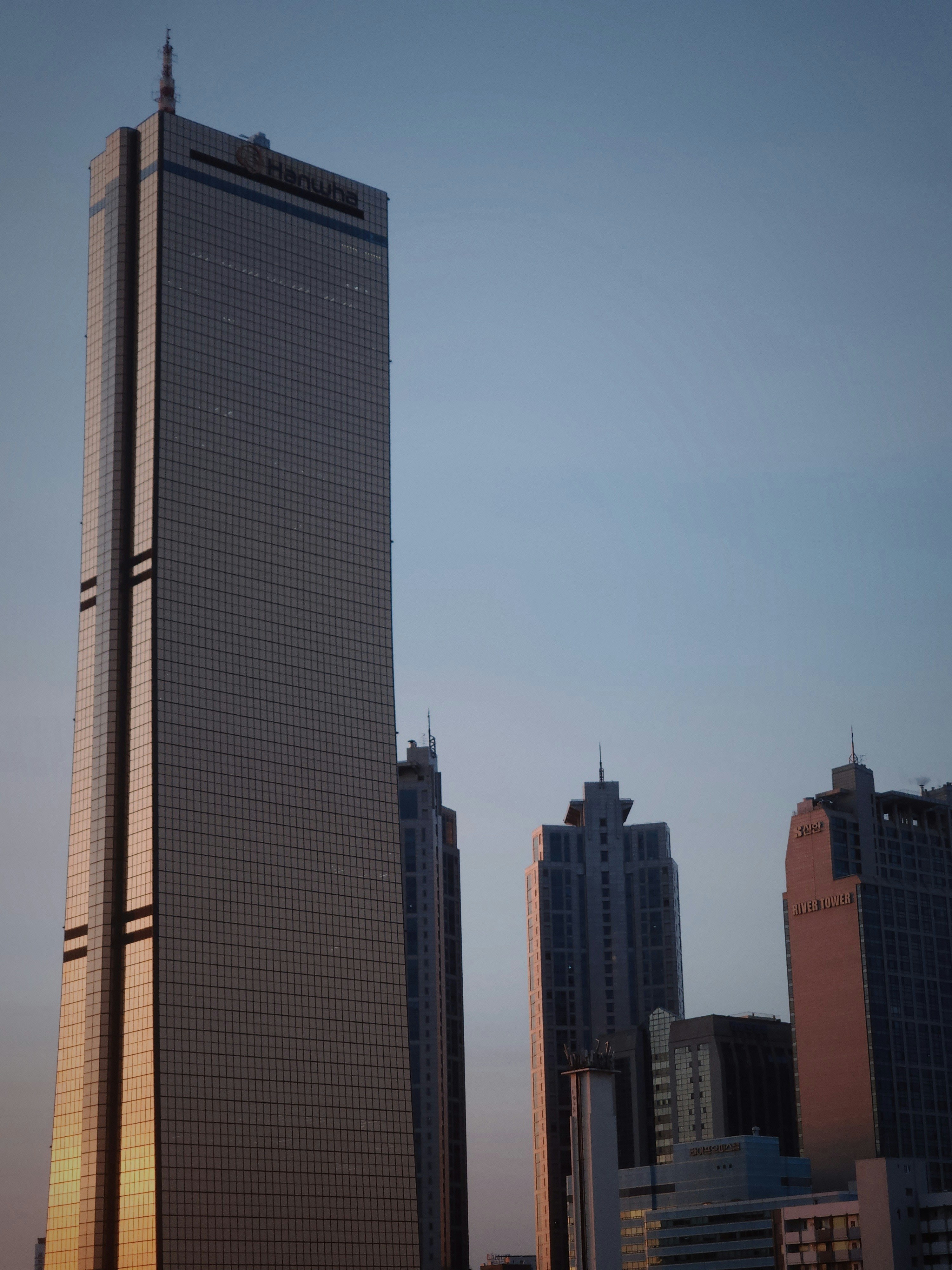 Tall office towers against a clear sky at dusk, around the time the workday ends