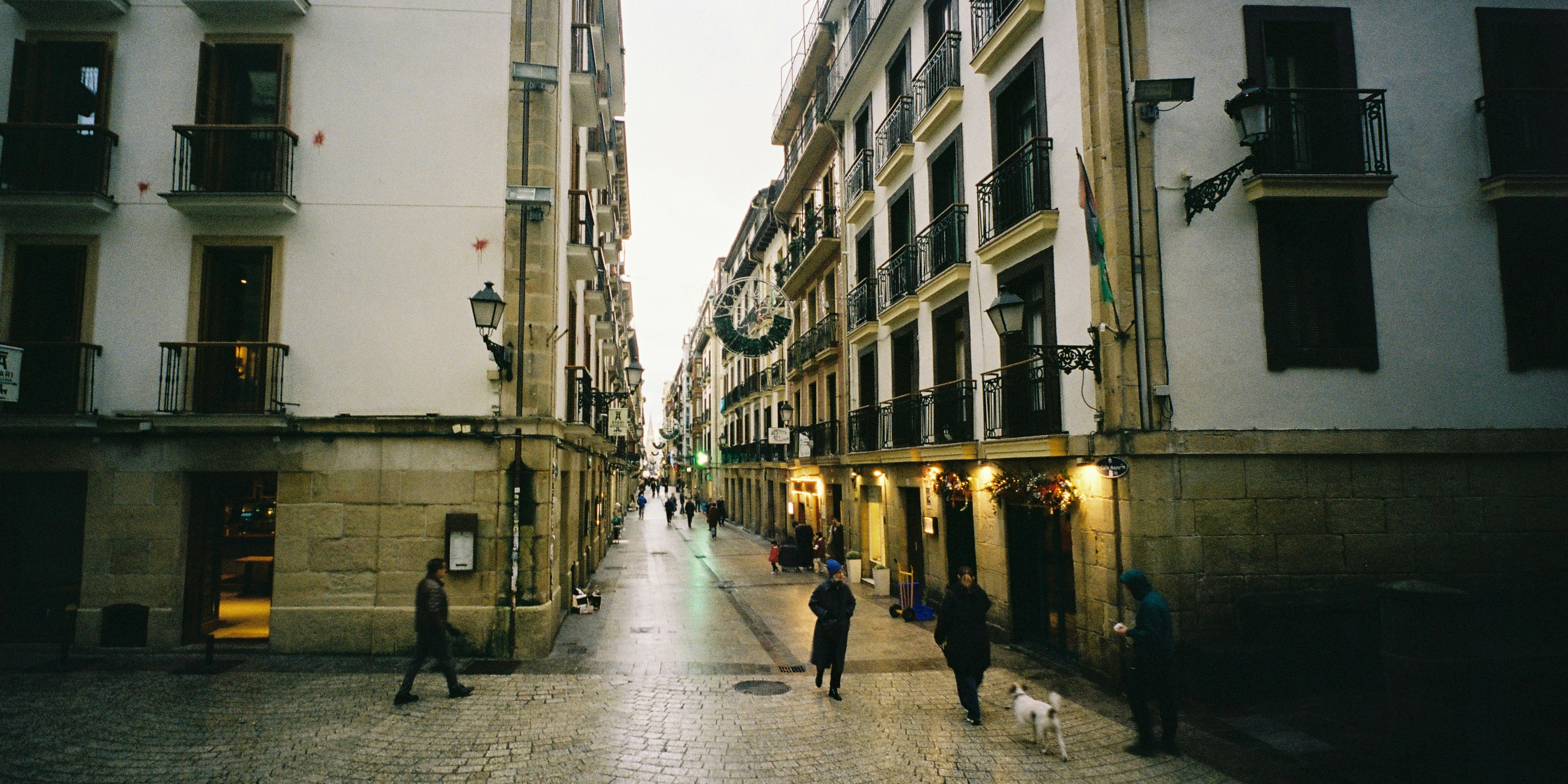 Wet city street with pedestrians and historic buildings