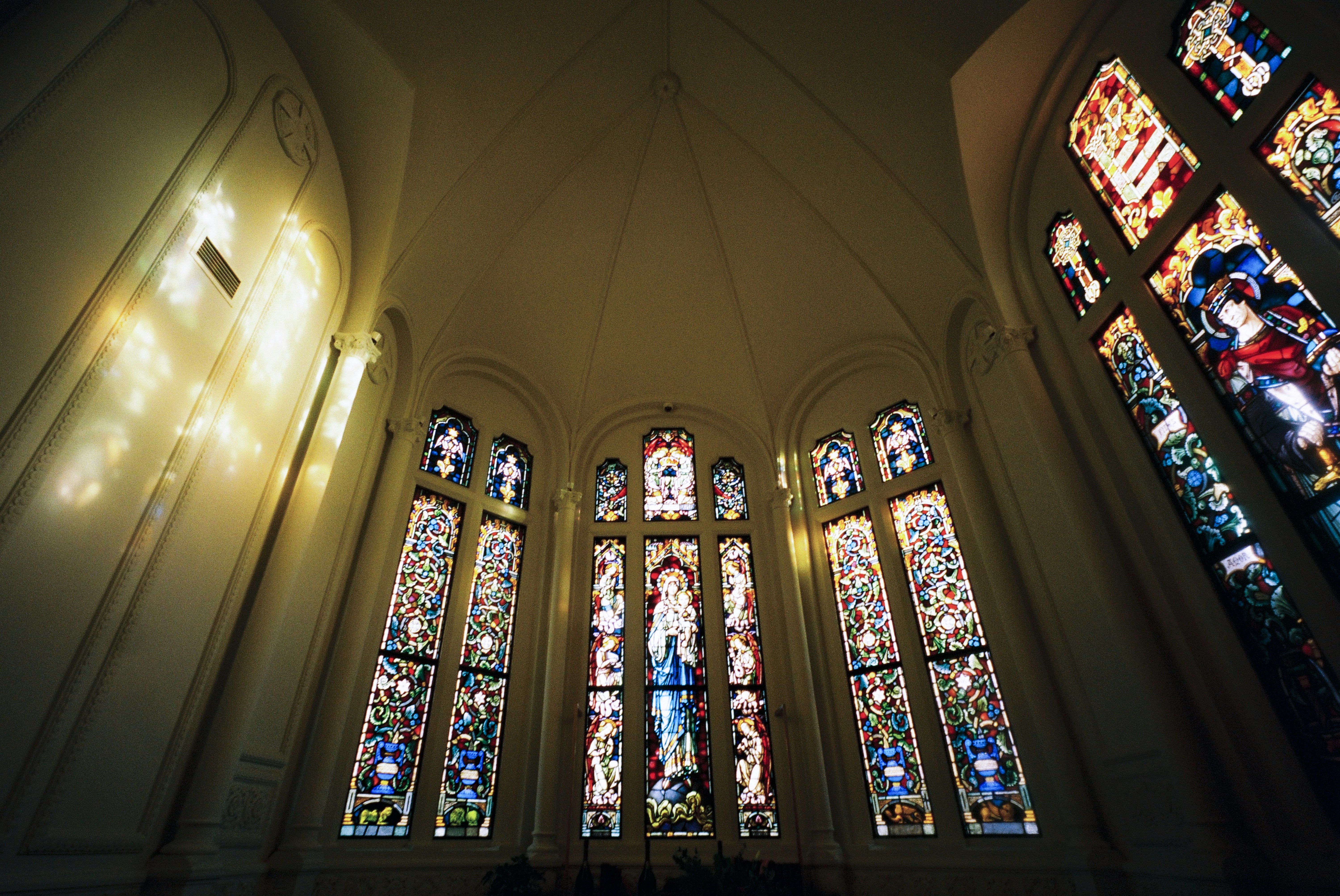Ornate stained glass windows illuminate a church interior