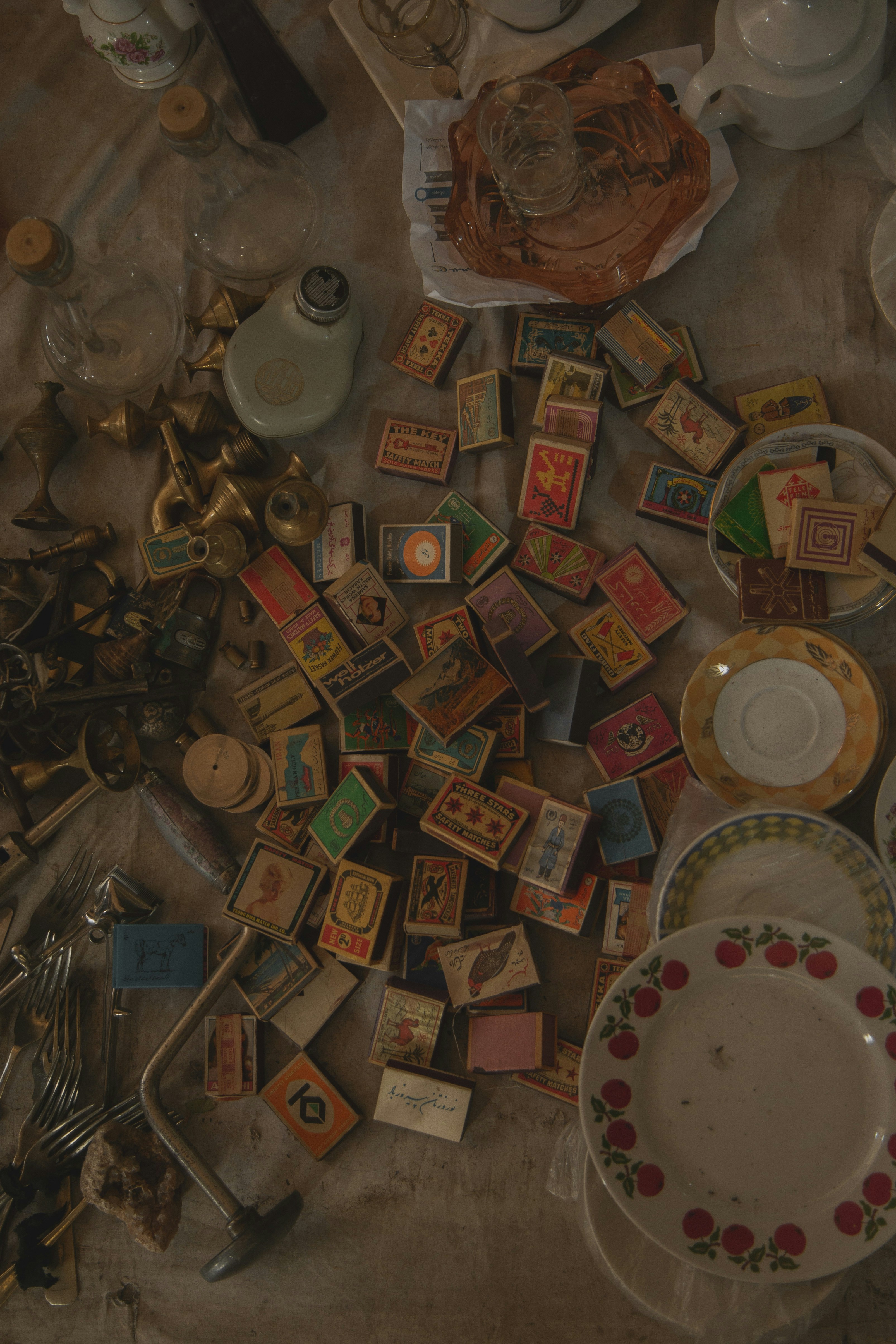 Collection of colorful vintage matchboxes surrounded by old household items.