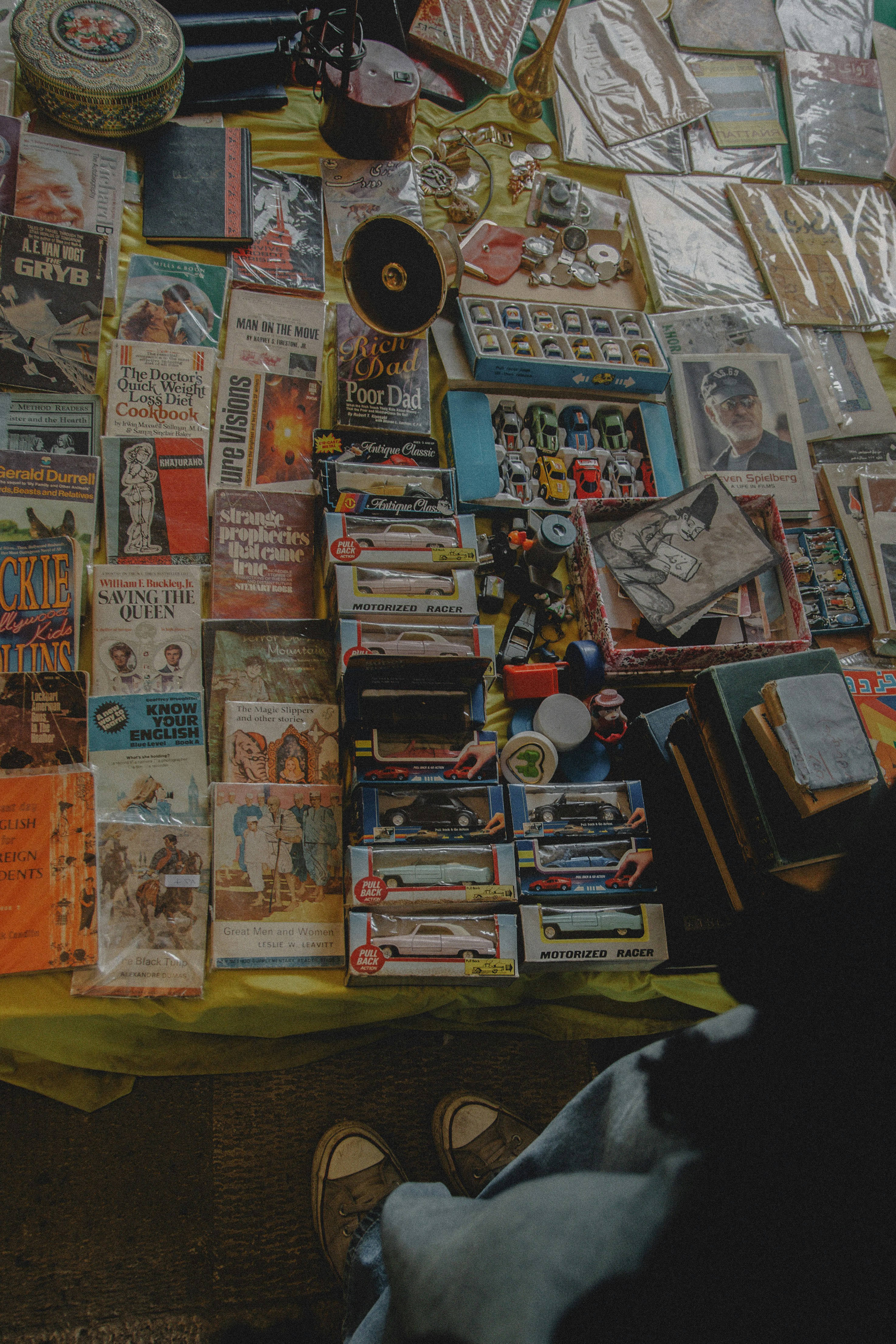 Assorted vintage books, toys, and items at a market stall.