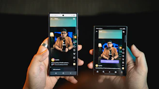 Hands holding two smartphones showing the same video
