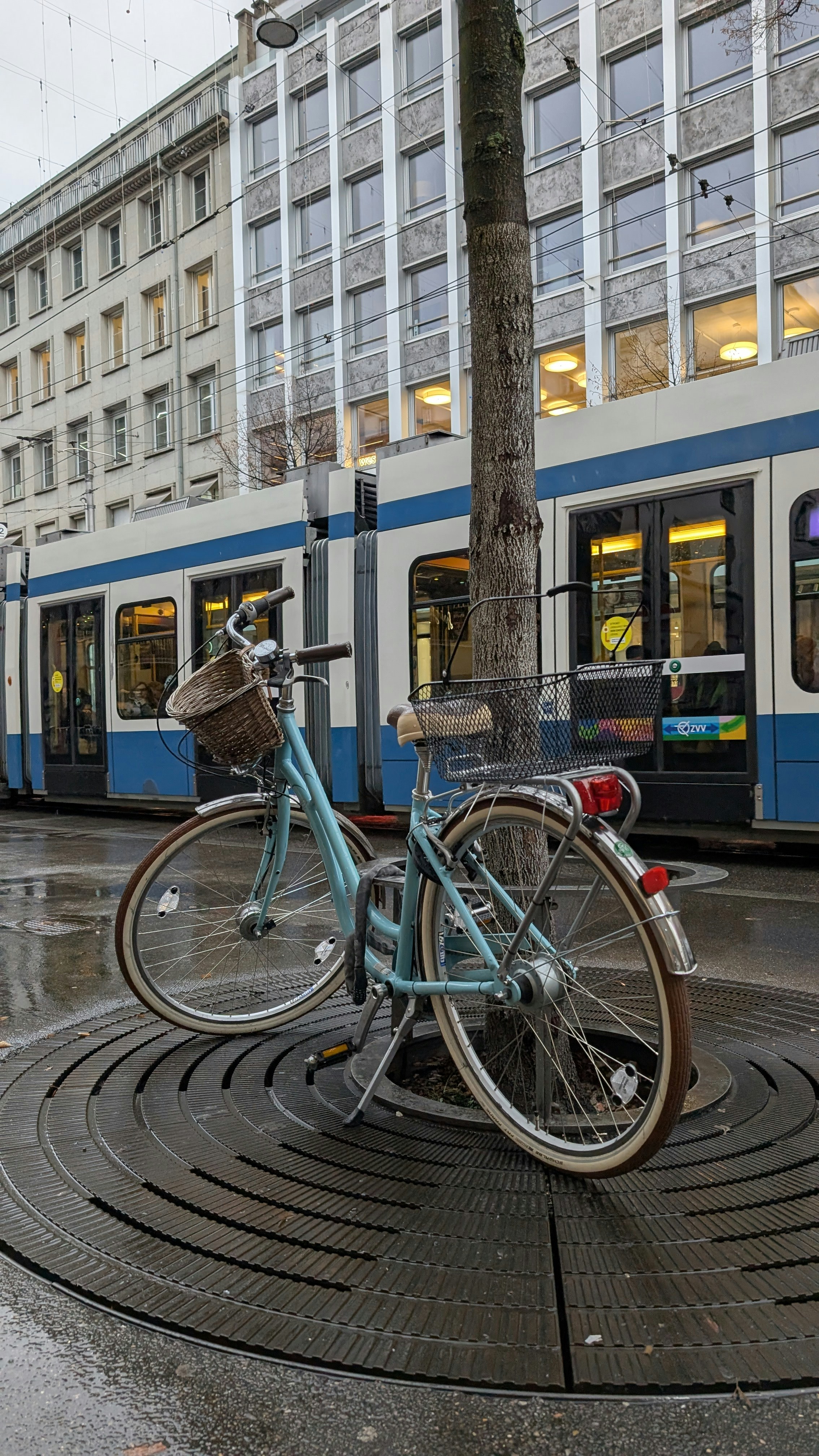 Bicicleta azul na rua molhada da cidade com bonde