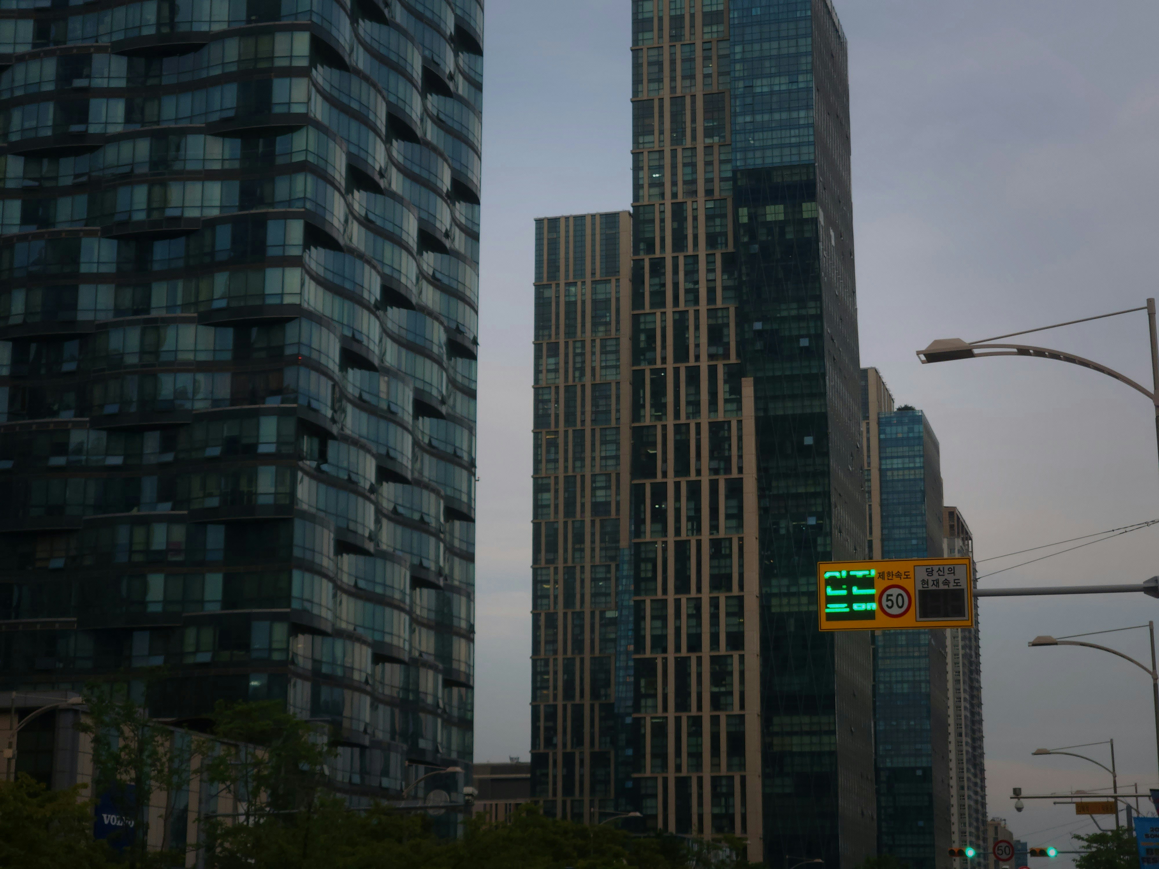 Modern skyscrapers and a street light against a cloudy sky
