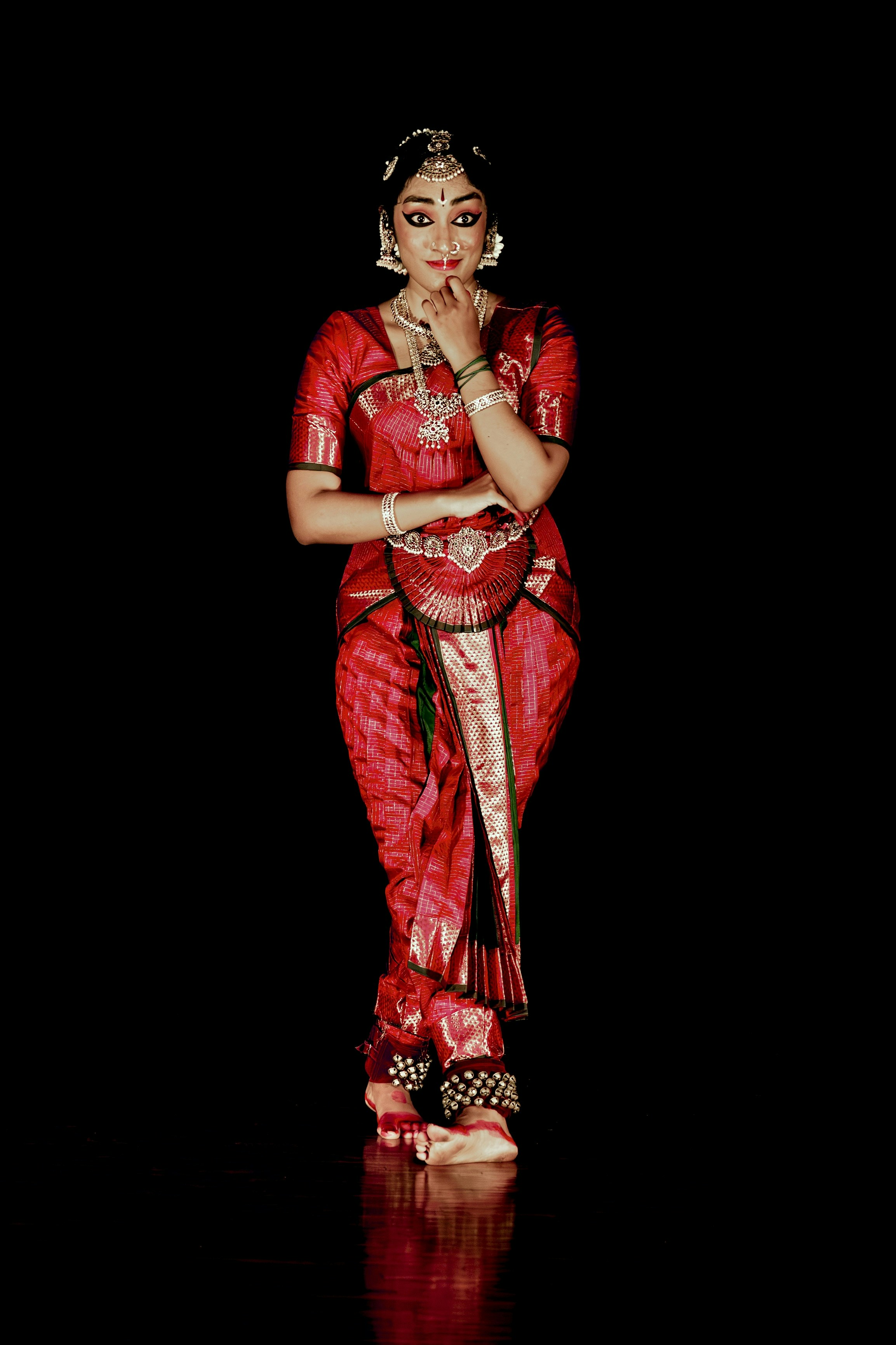 Elegant indian dancer in red traditional attire posing.