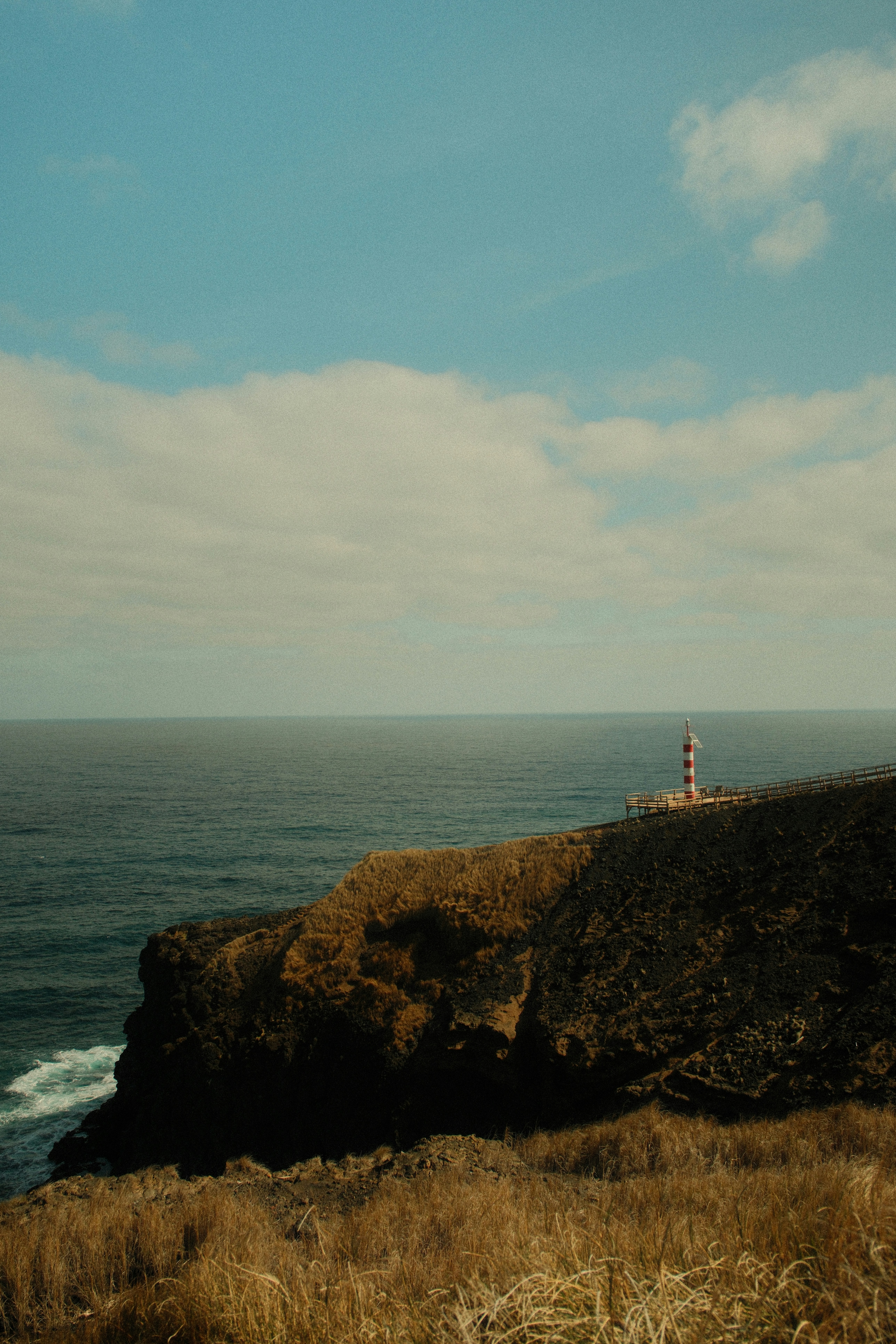A lighthouse stands on a rocky cliff overlooking the ocean