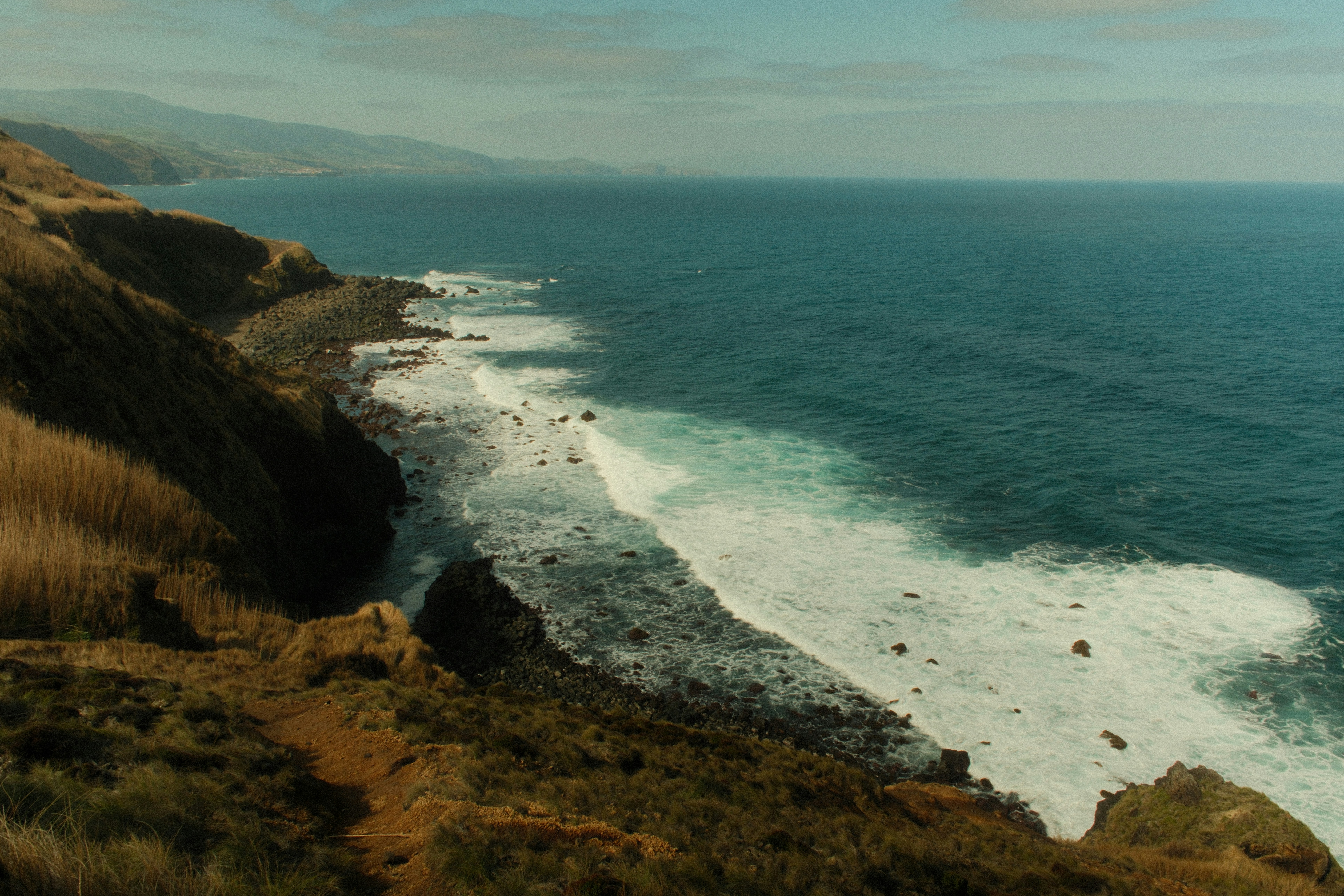 Waves crash on a rocky coastline under a clear sky