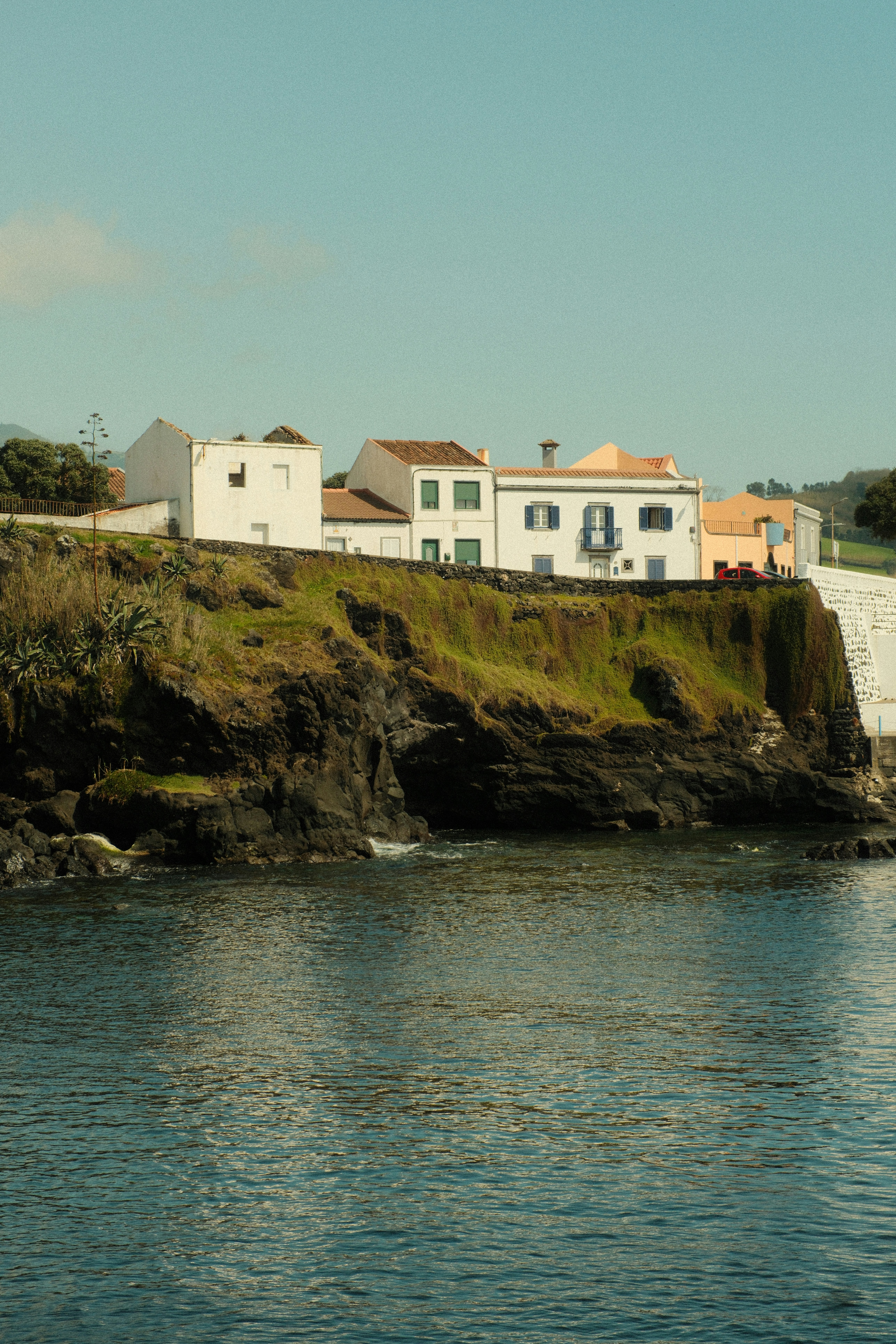 White buildings on a rocky cliff overlooking blue ocean