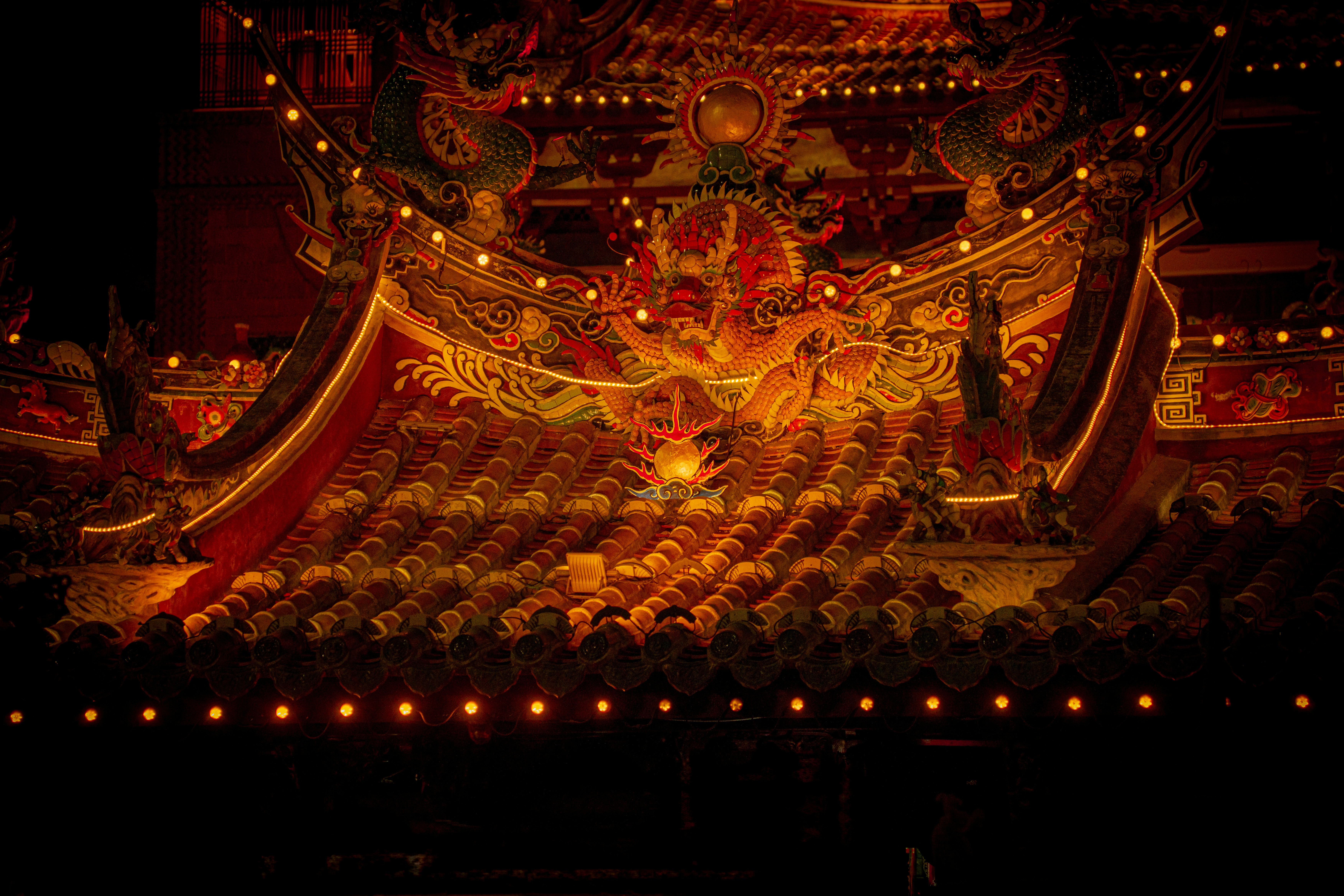 Ornate chinese temple roof glowing with lights at night