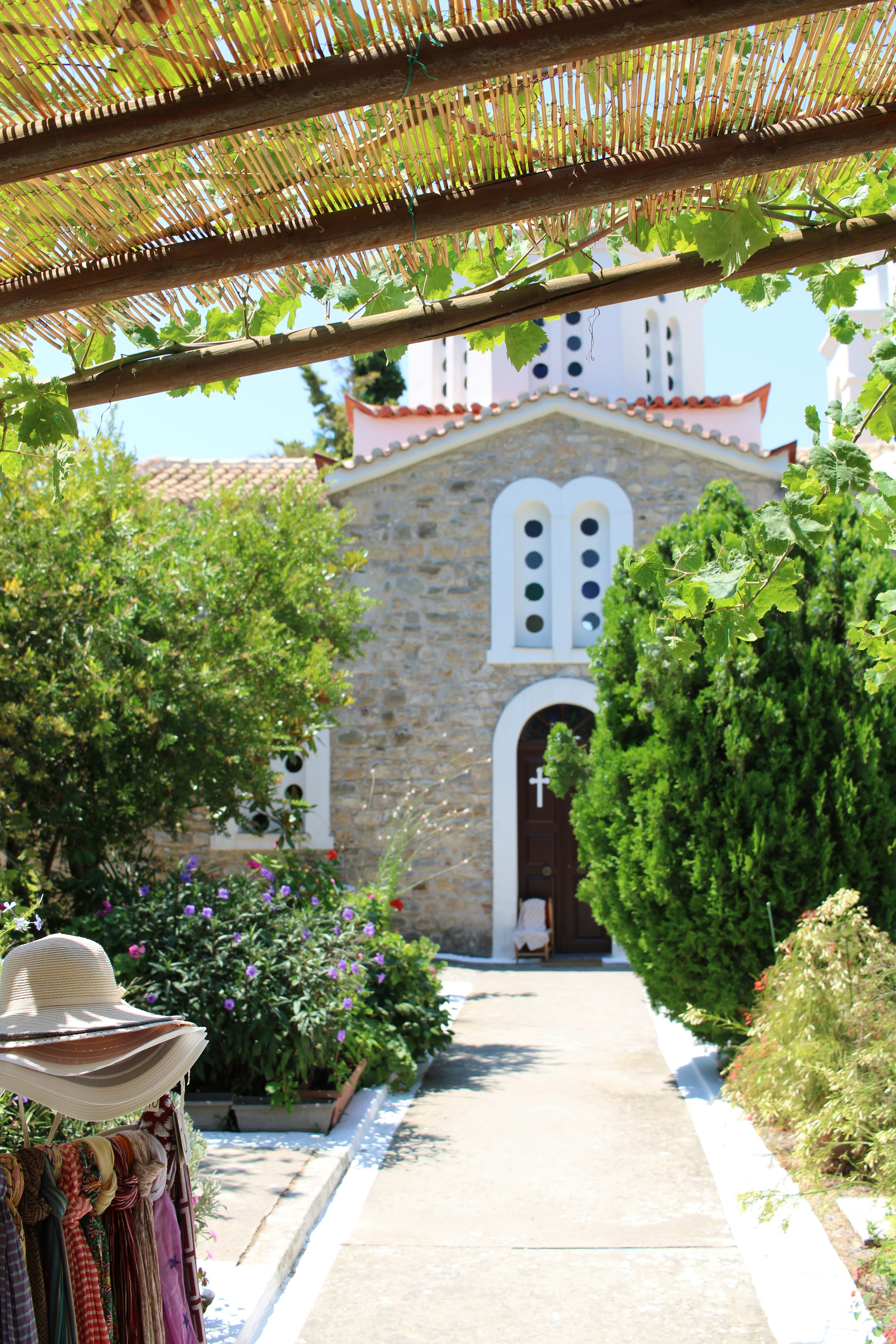 Pathway leading to a stone chapel under a leafy trellis