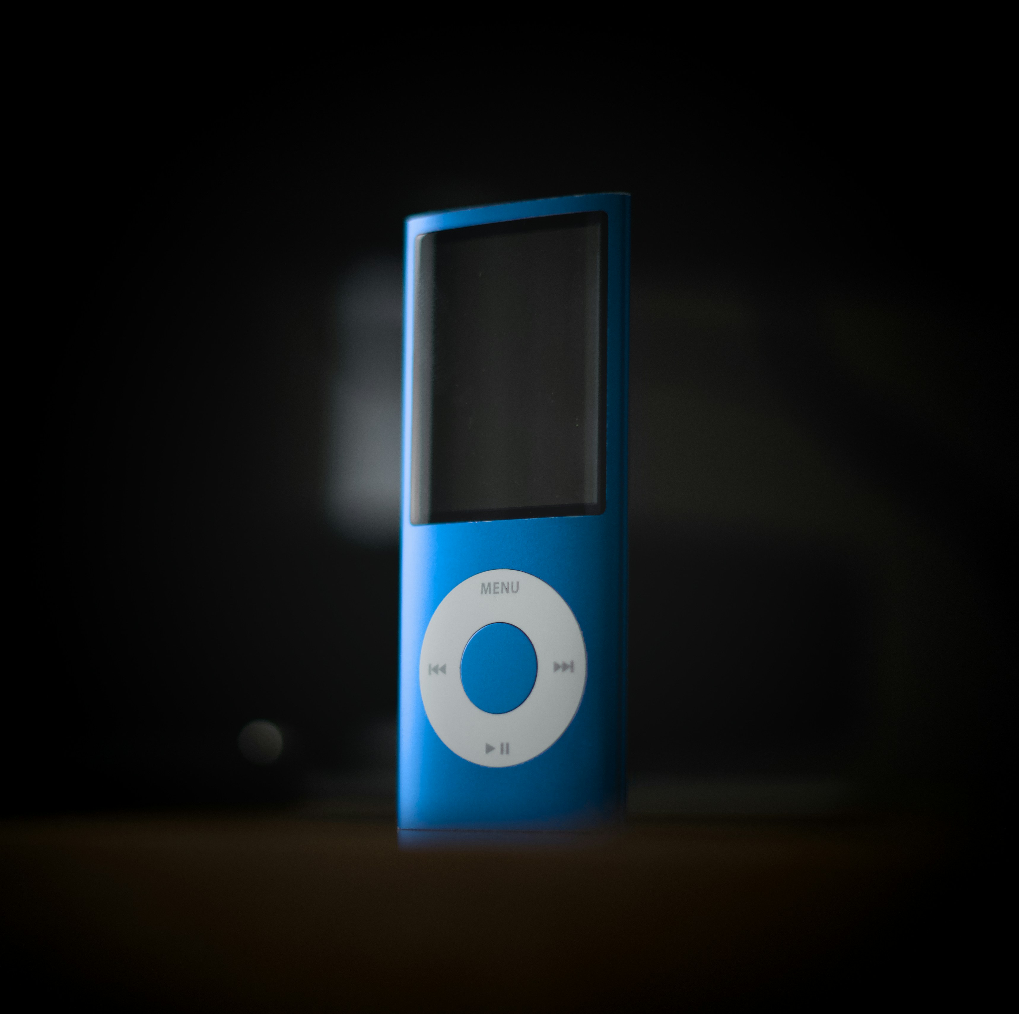 A blue iPod nano stands upright against a dark background