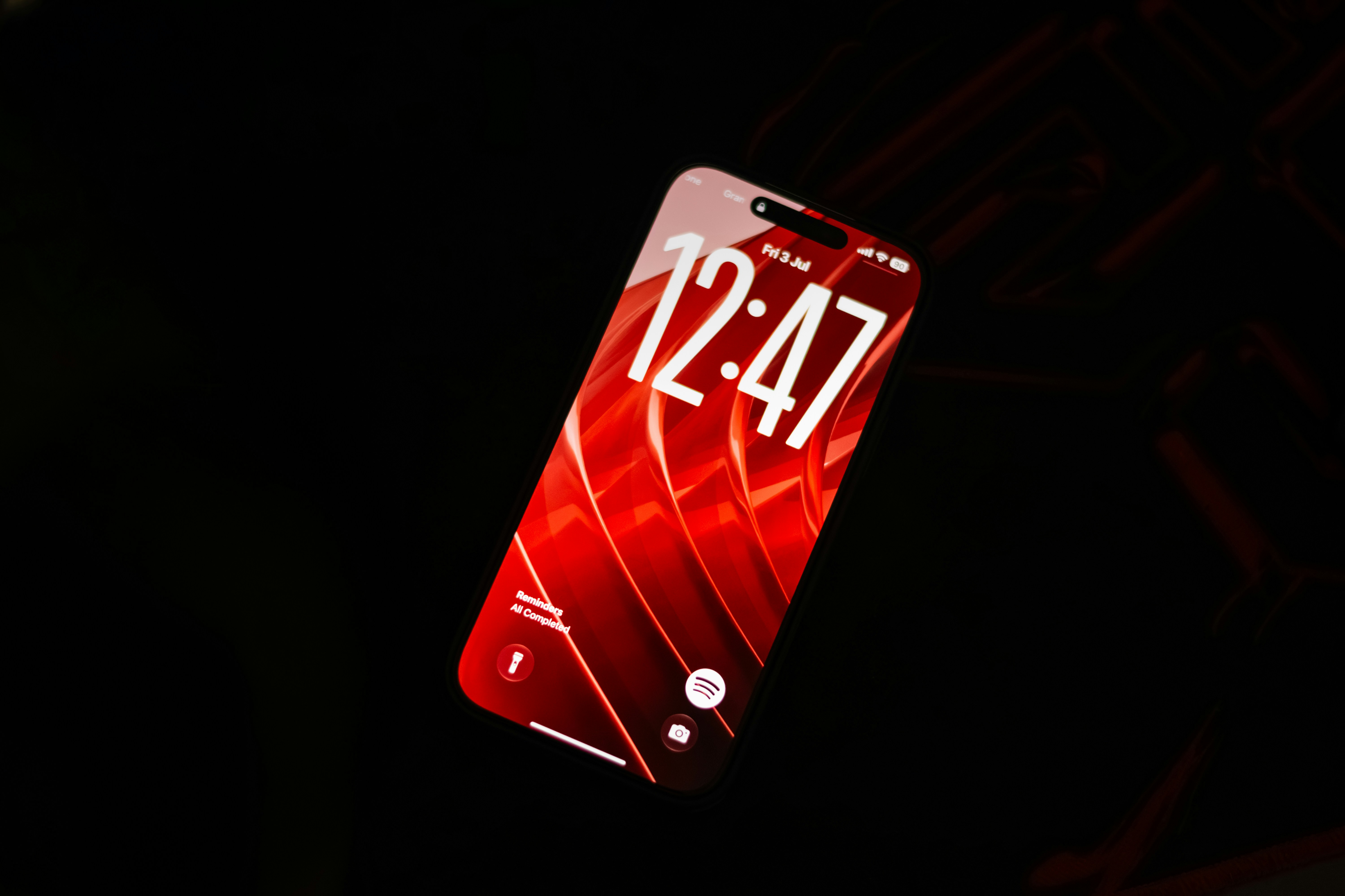 A smartphone with a red screen displaying the time 12:47