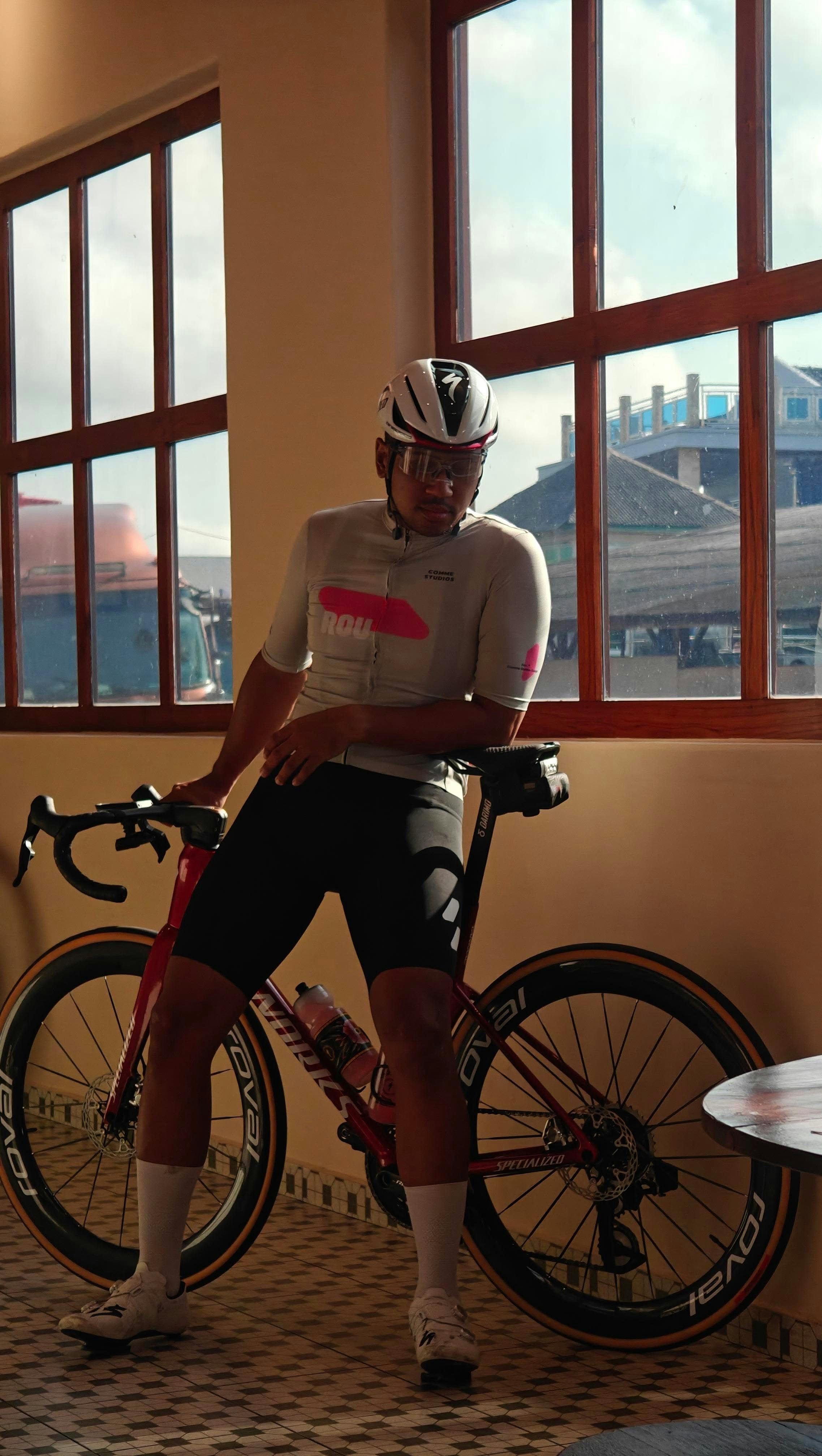 Male cyclist resting with his road bike by a window