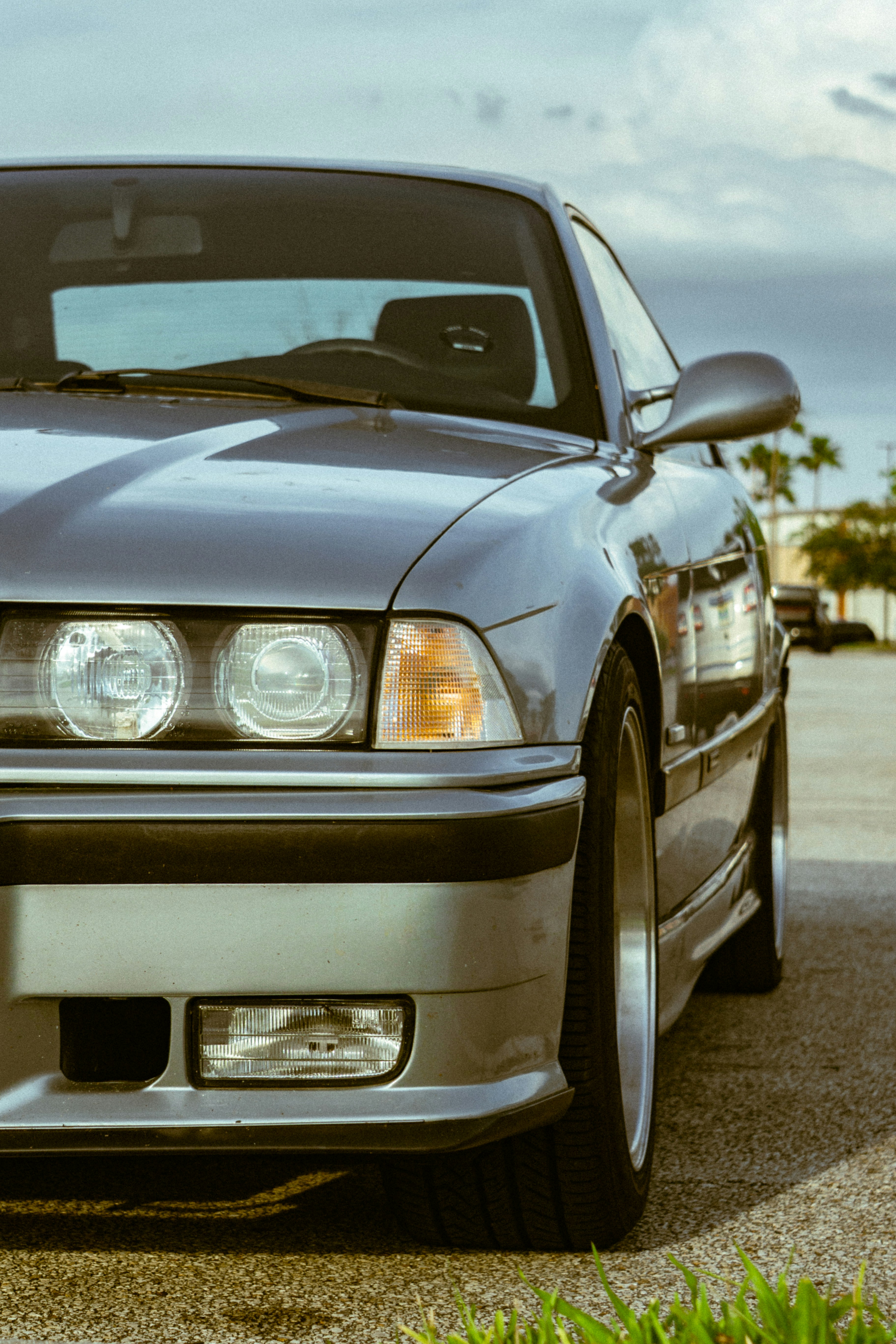 Front side of a grey car parked outside.