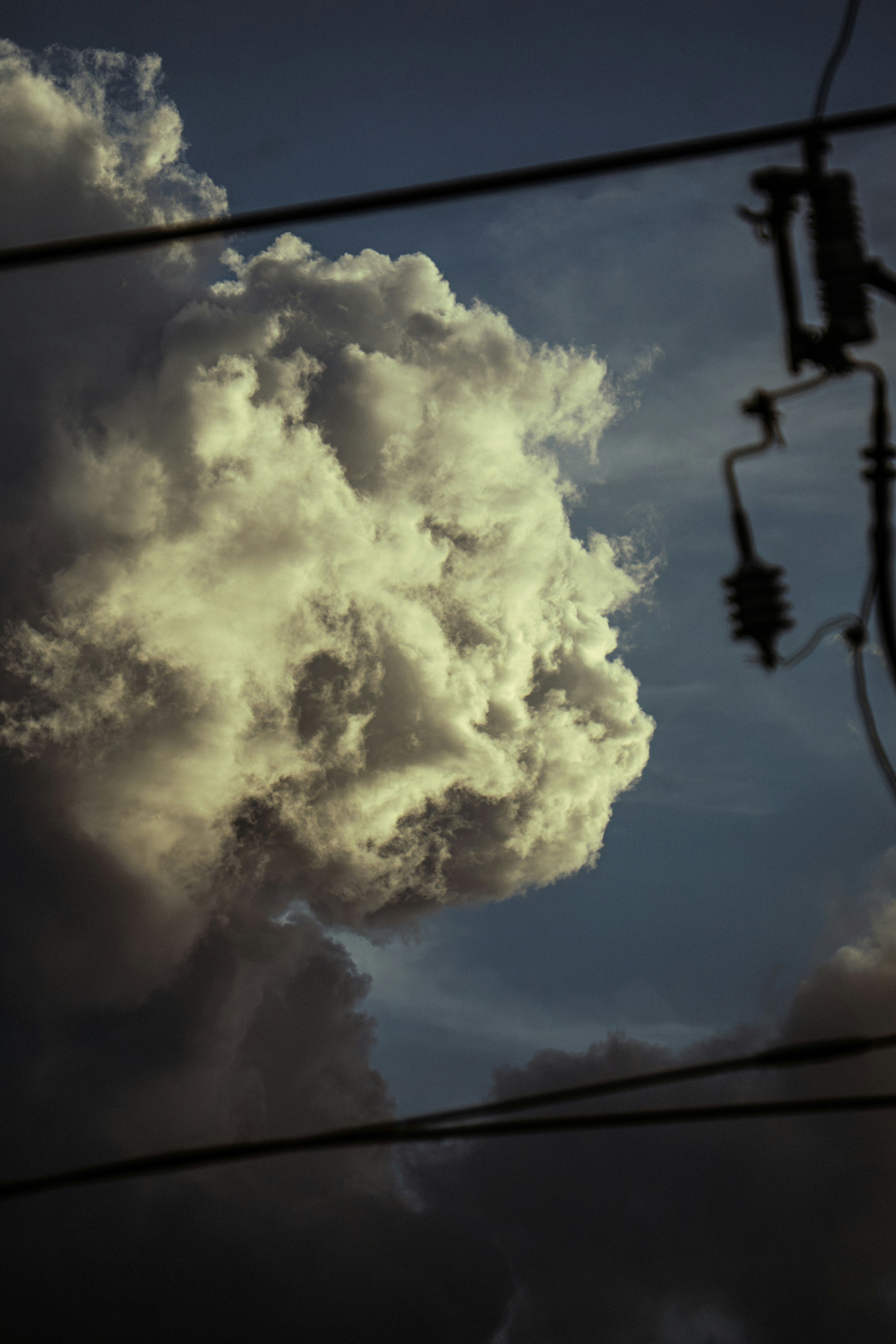 Dramatic clouds and power lines against a dark blue sky.