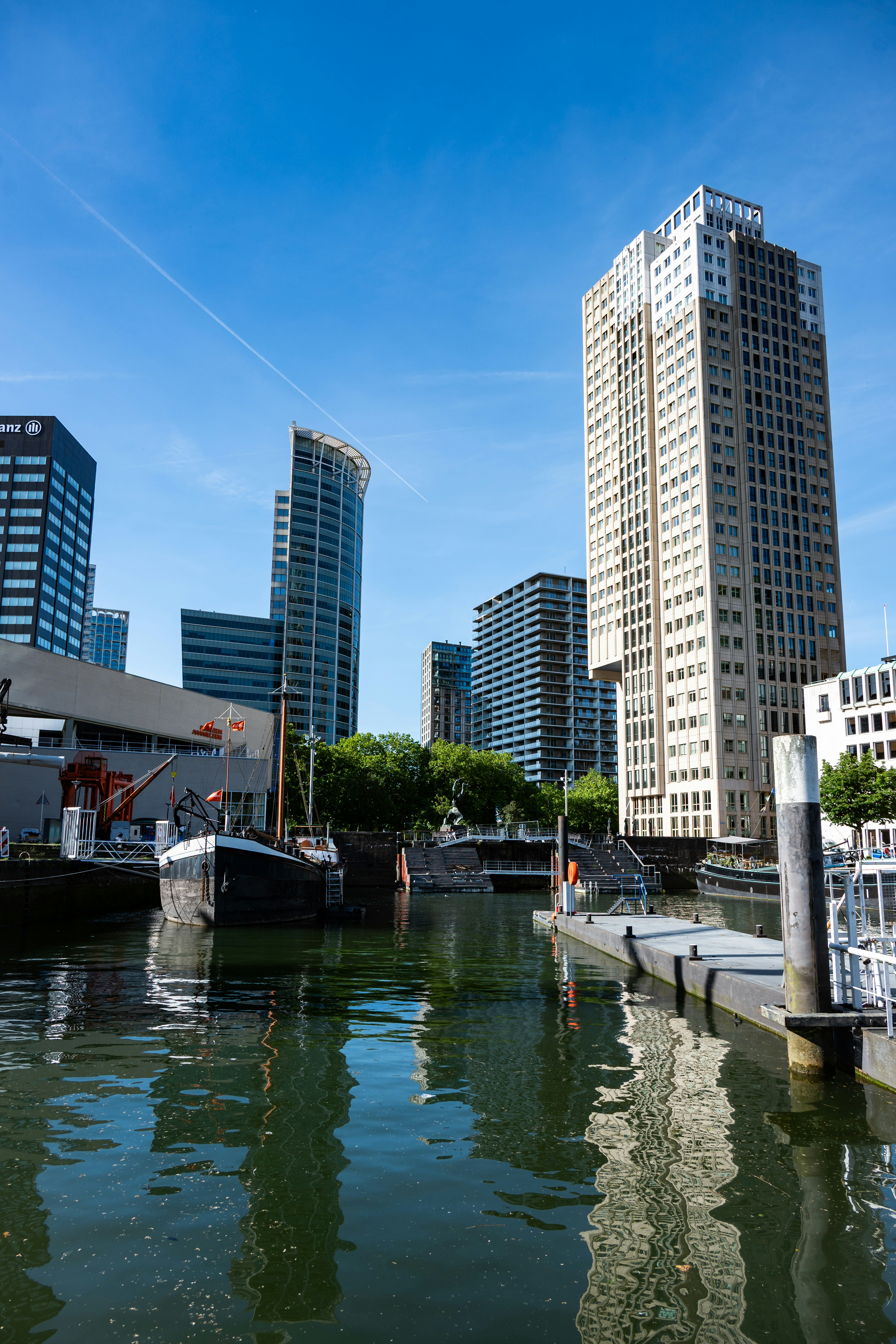 Hohe Gebäude spiegeln sich in einem Stadtkanal mit angelegten Booten wider.