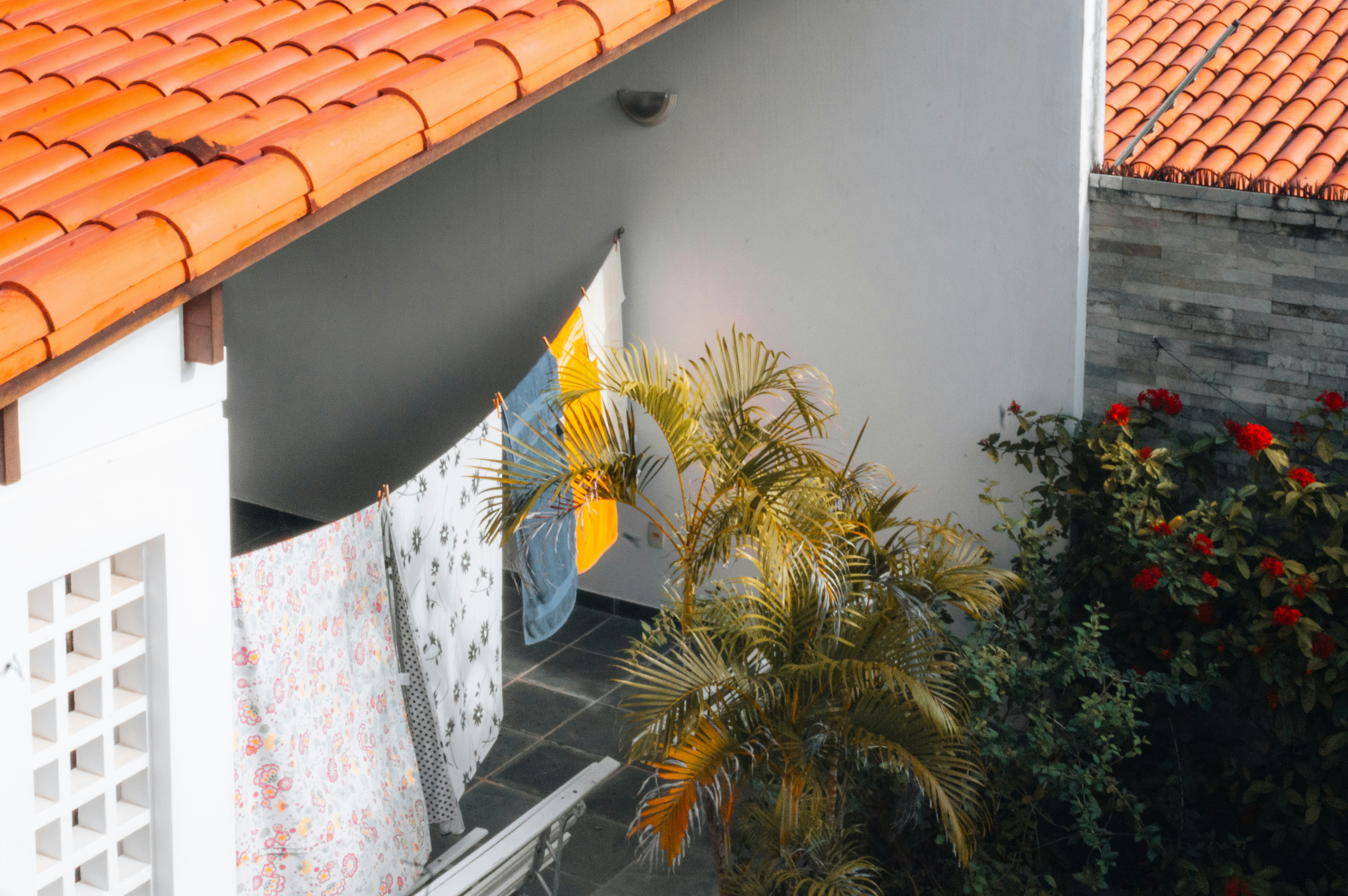 heavy rain on residential roof - Courtyard with orange tiled roof, laundry, and green plants