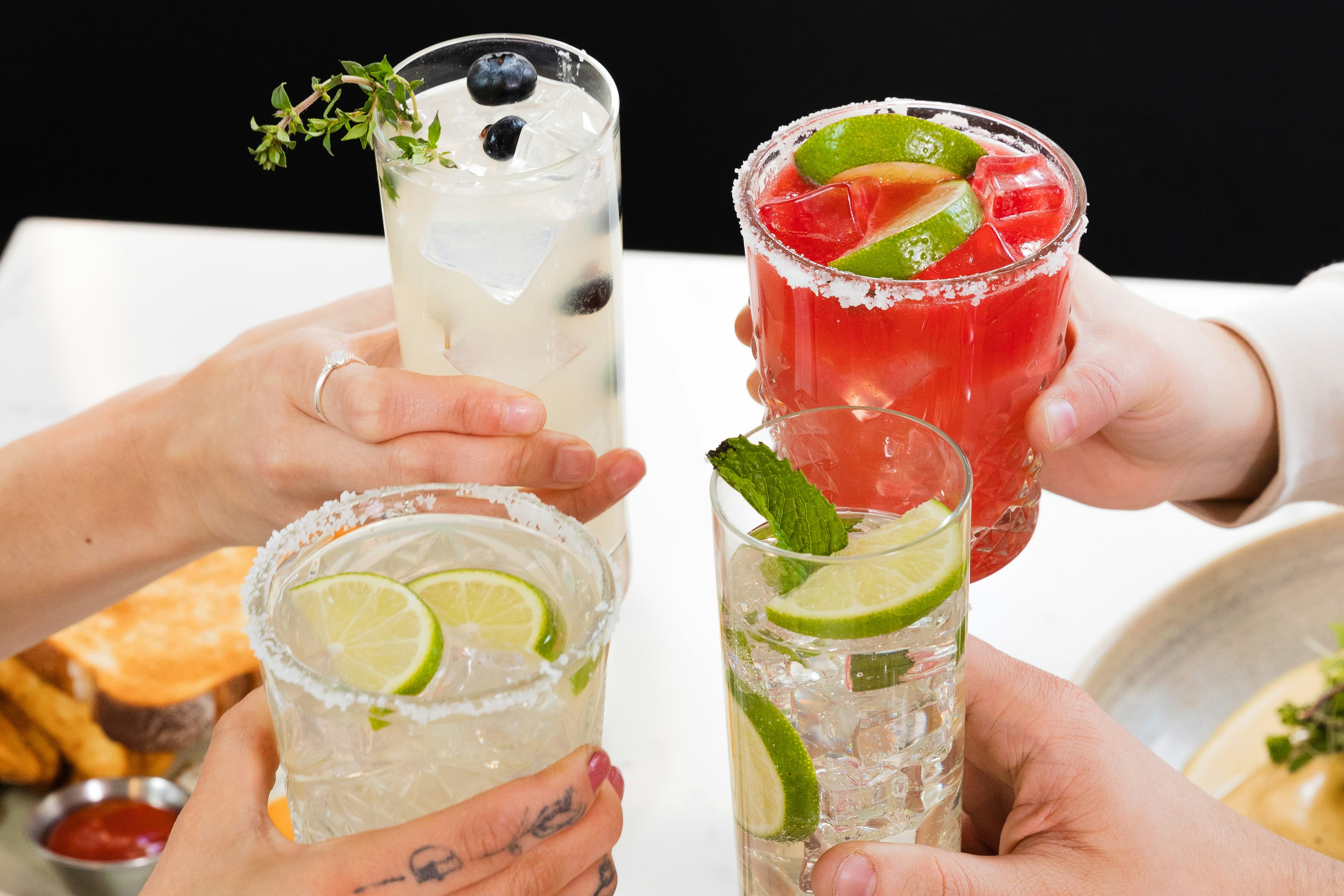 Freunde, die mit erfrischenden Limetten-Beeren-Cocktails anstoßen