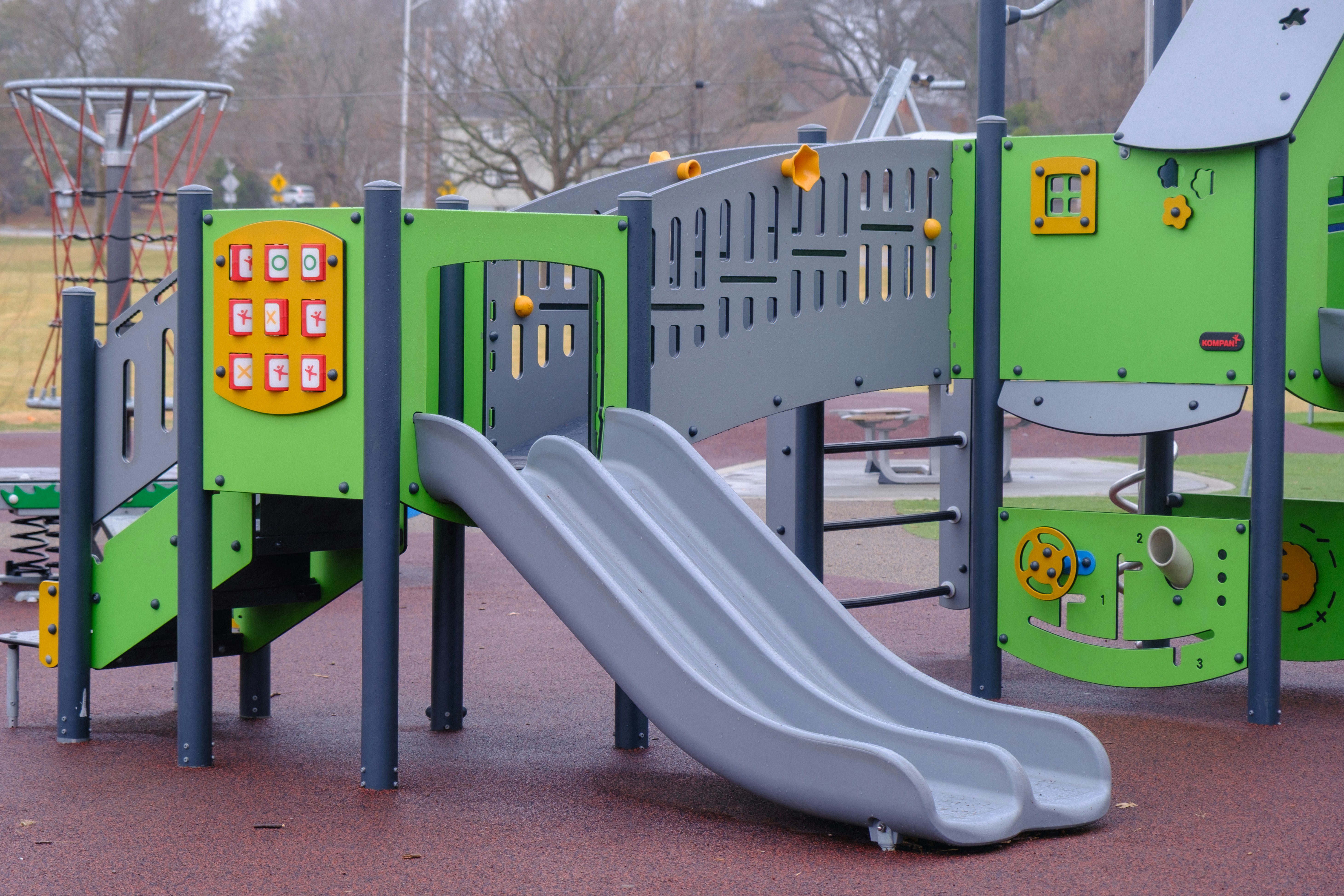 Empty outdoor playground with green structures and slides
