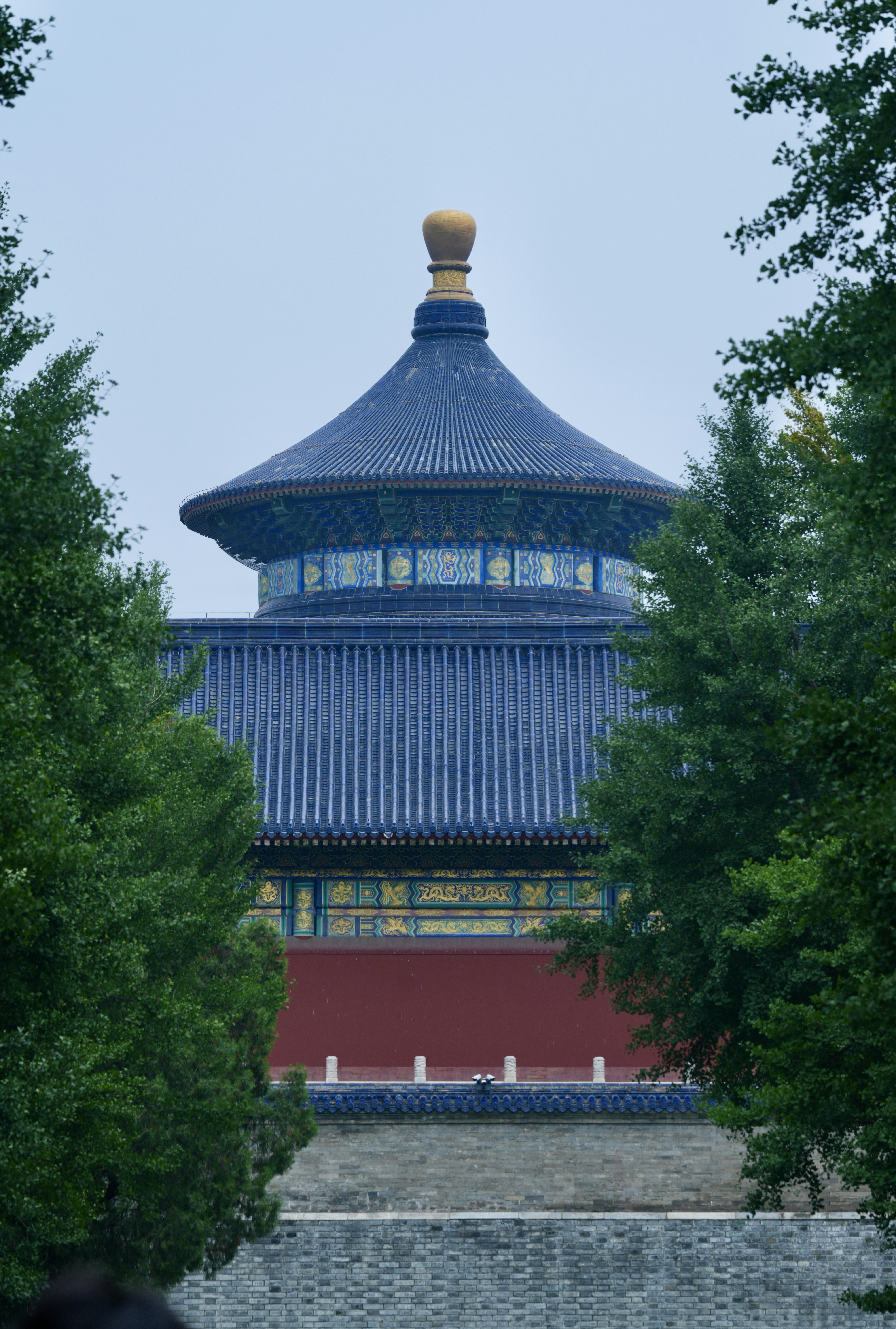 Blue-roofed temple building framed by lush green trees.