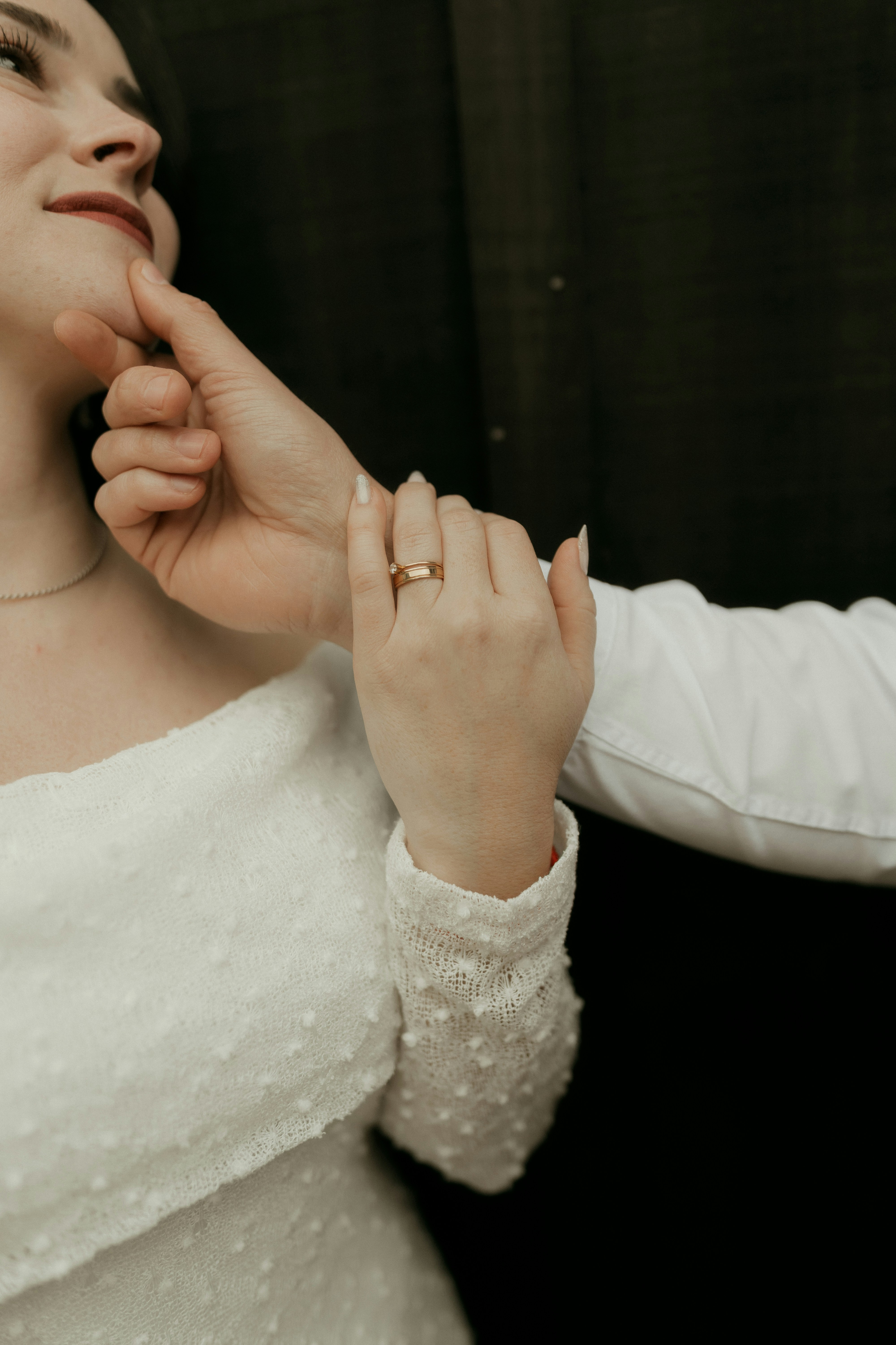 Woman in white dress holding hands, wearing a ring.