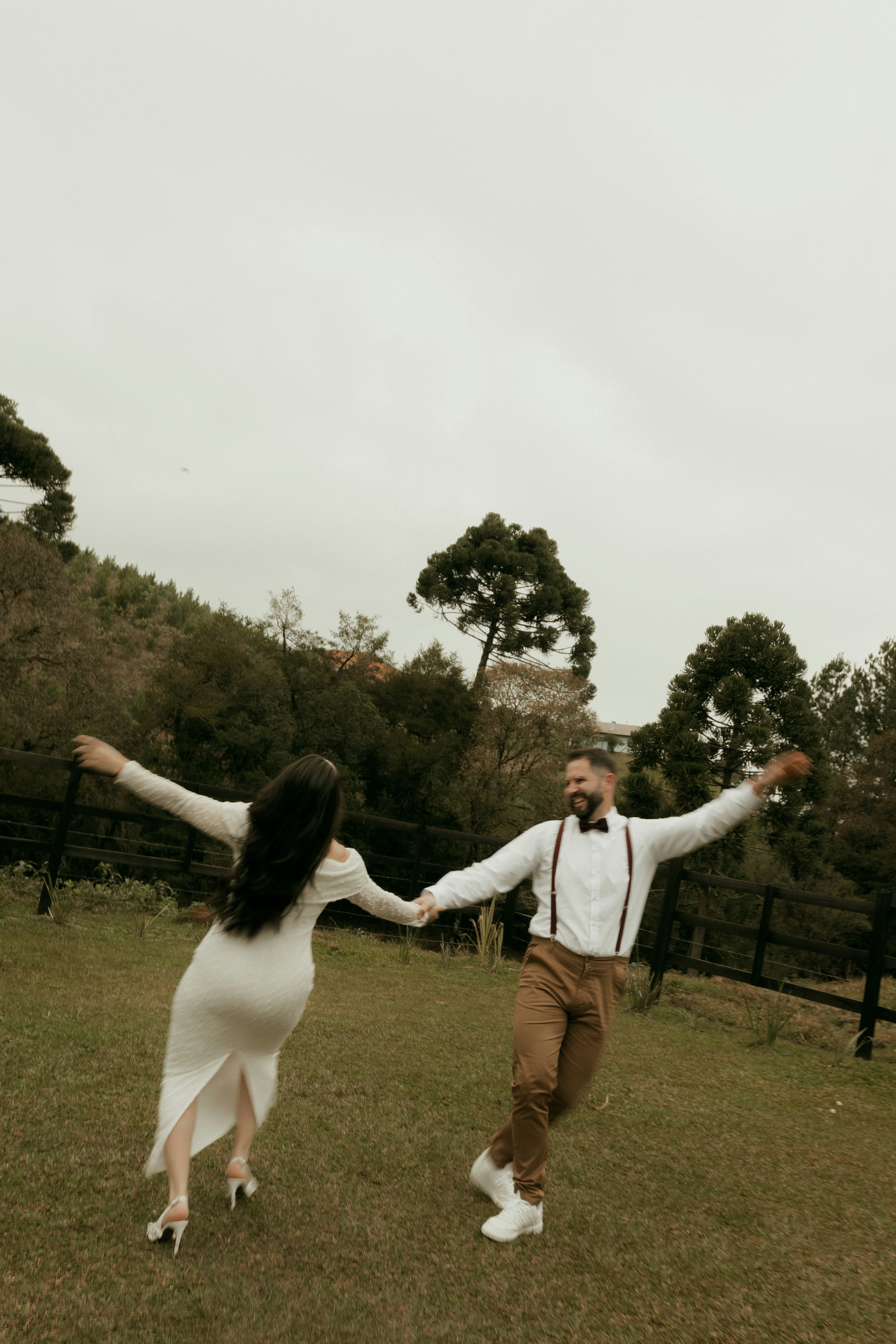 A joyful couple dancing outdoors in a grassy field.