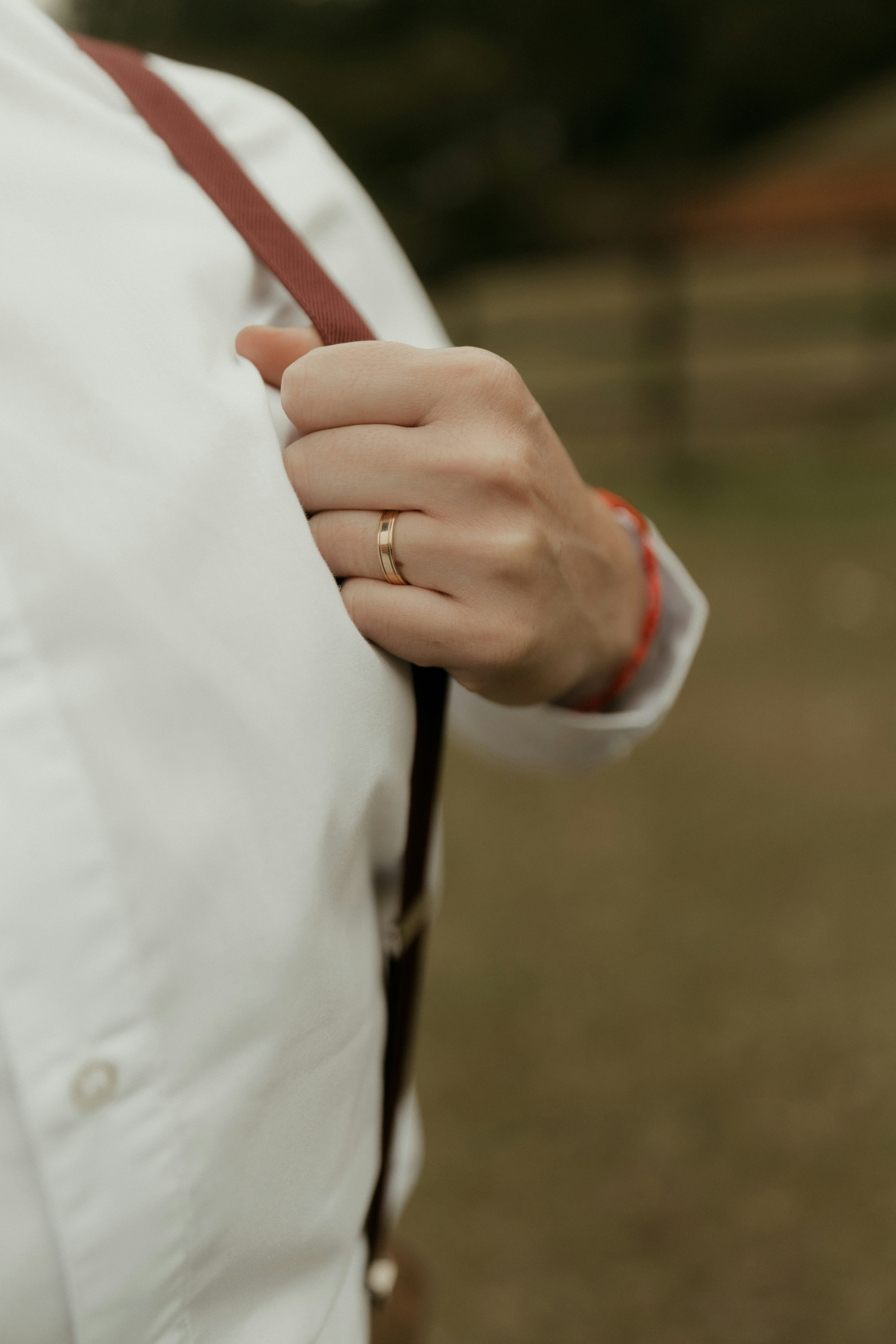 Una mano con un anillo sujetando una tirante roja