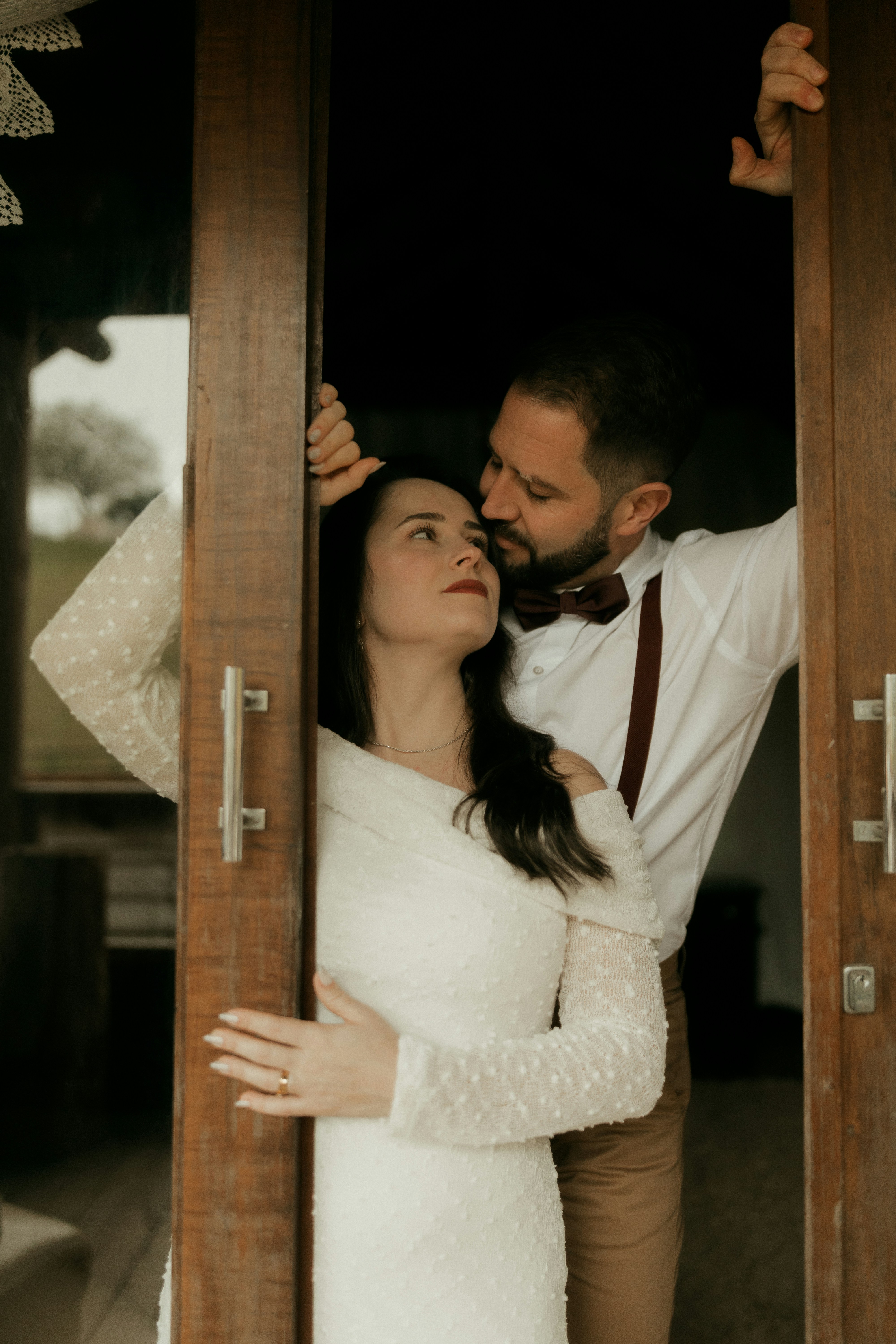 Couple shares an intimate gaze framed by wooden doors.