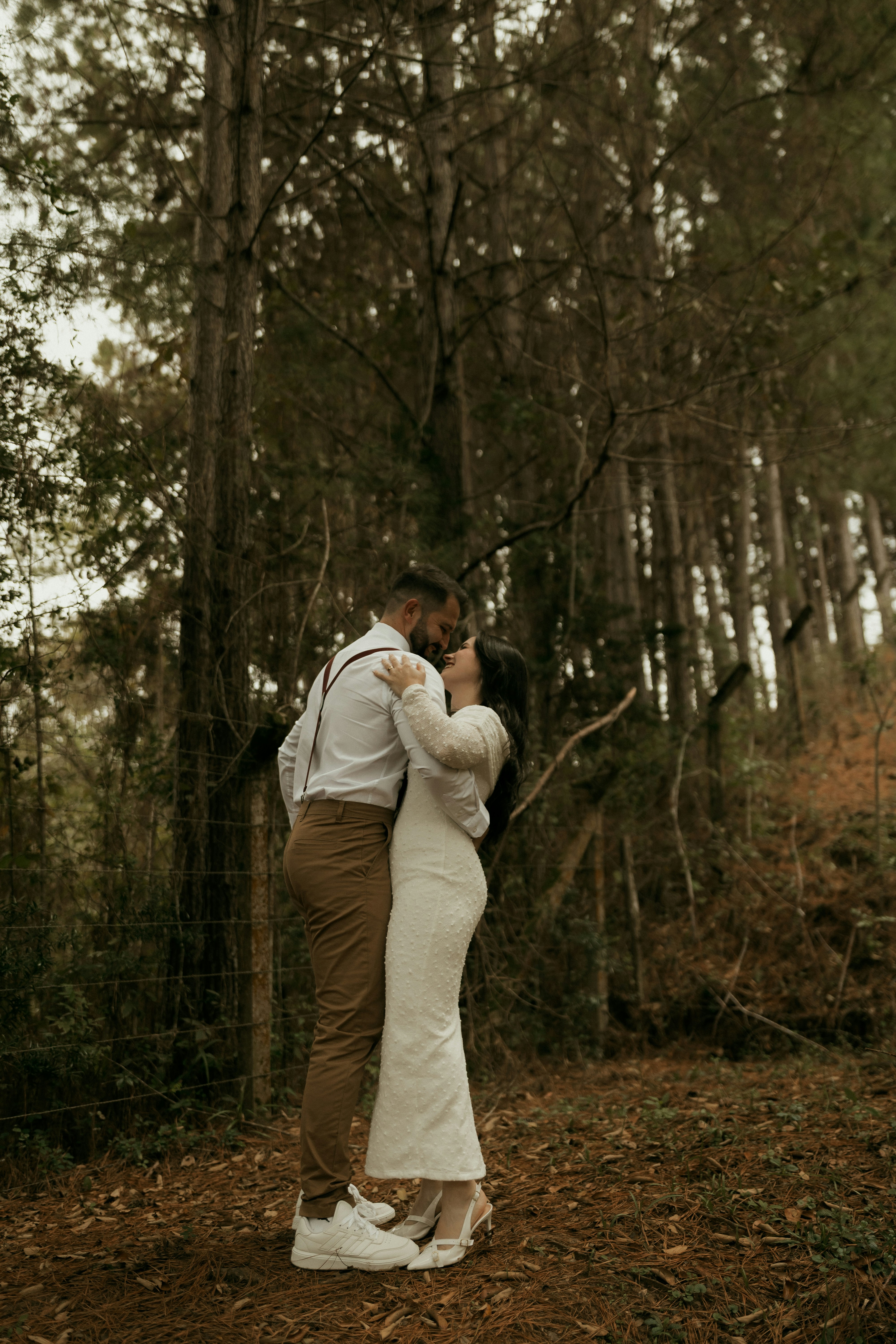 A loving couple embraces in a dense forest.