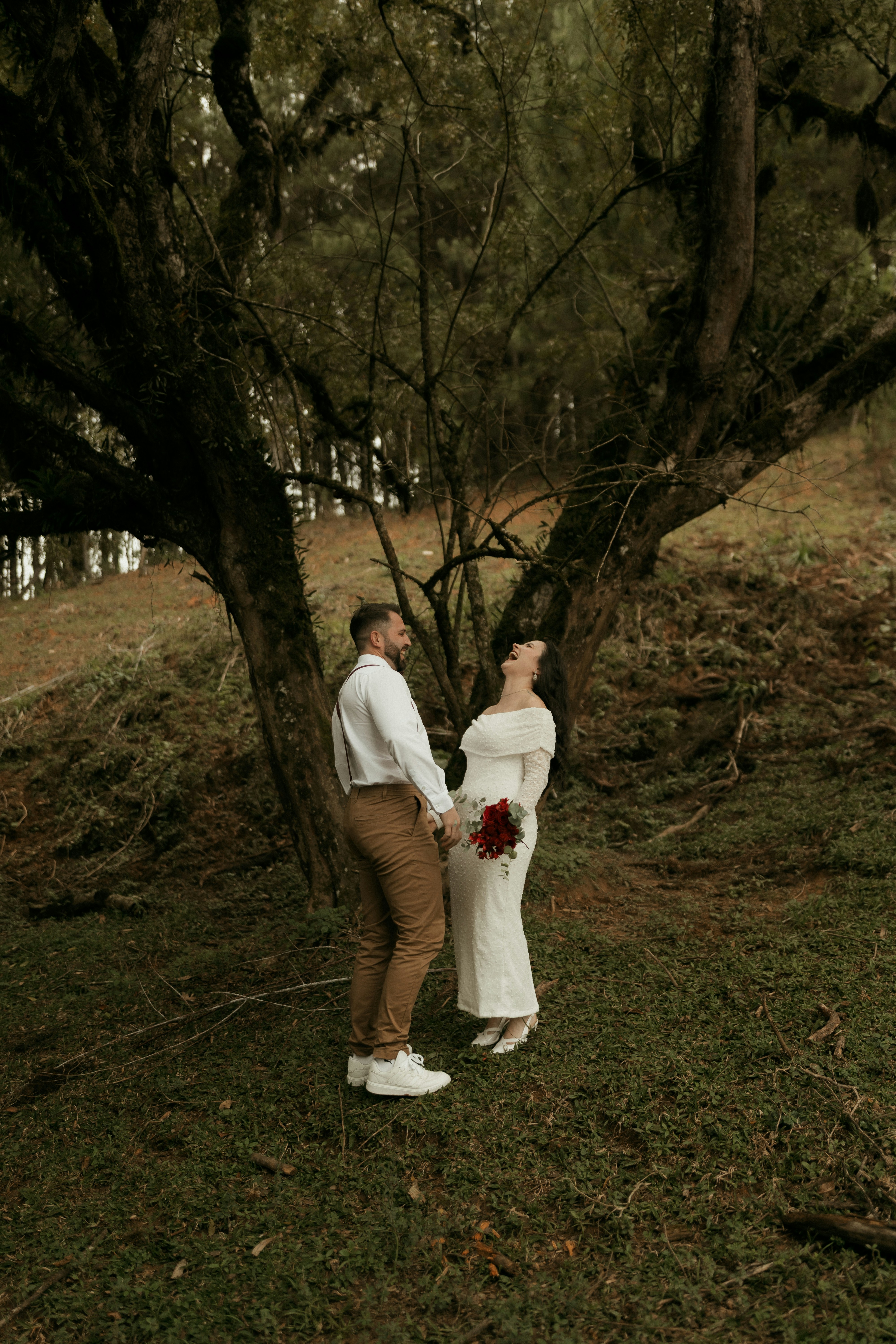 A happy couple laughing together under a large tree.