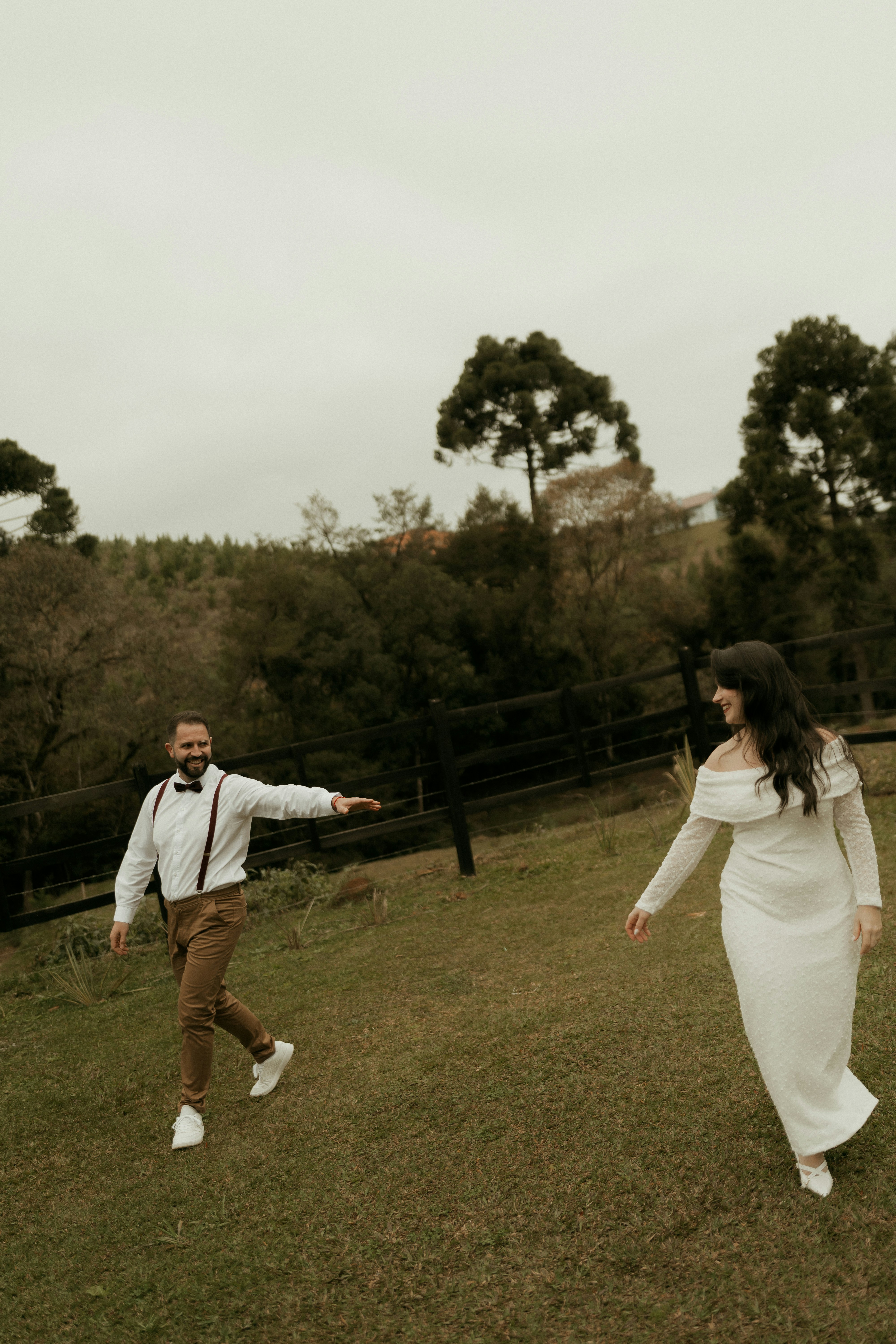 Happy couple in formal attire dancing on a grassy field.