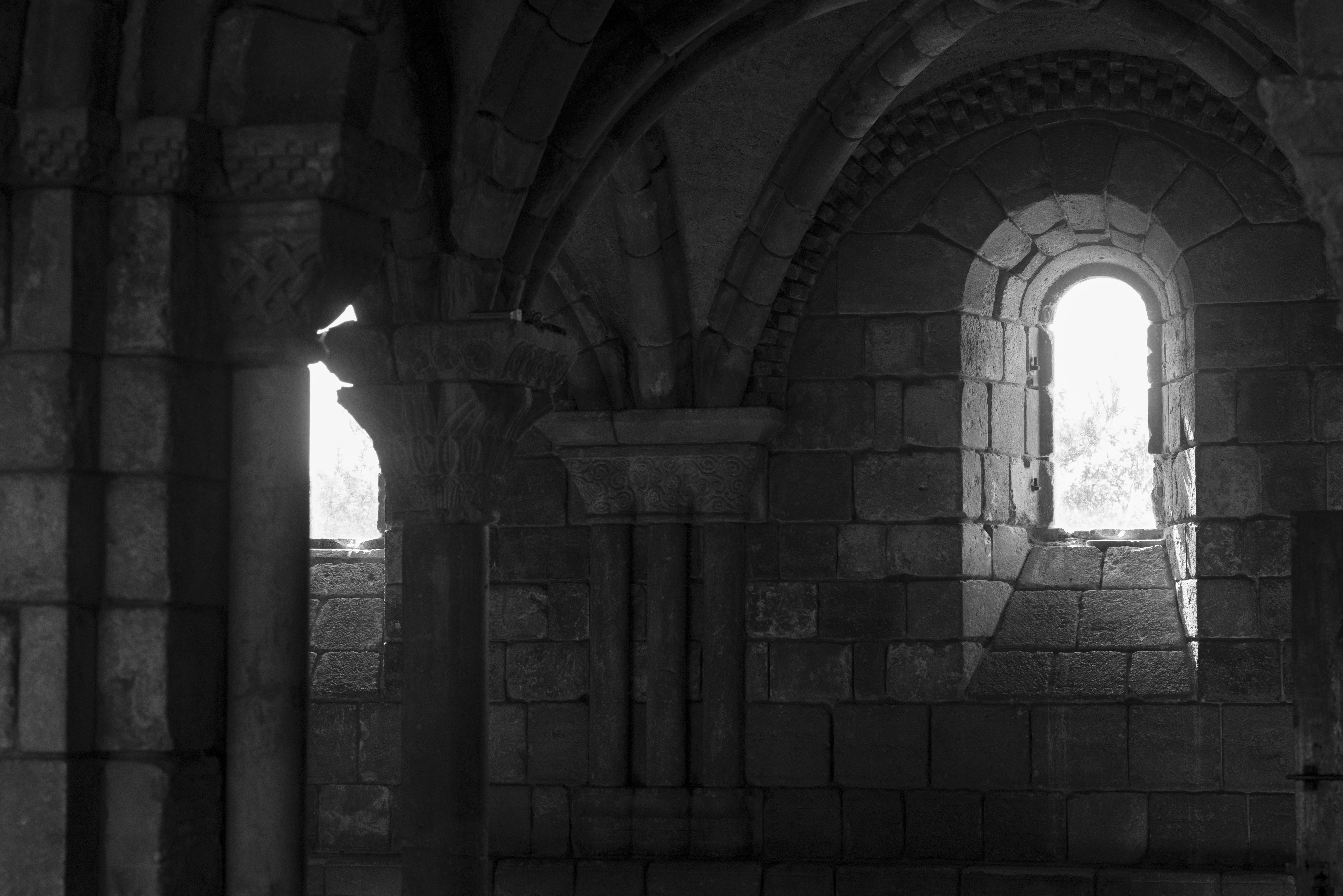 Ancient stone church interior with arched windows and light